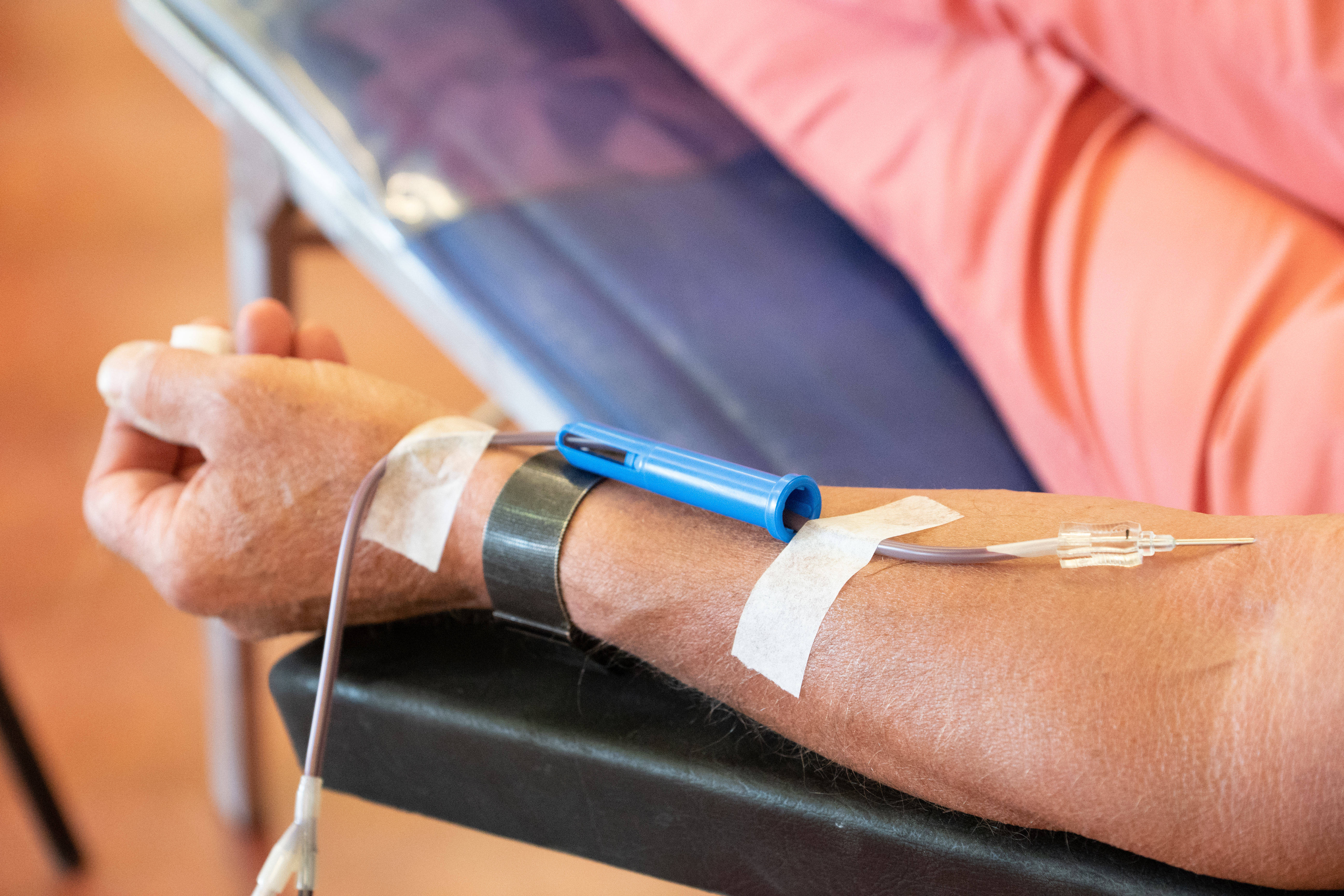 Ein Blutspender sitzt auf dem Liegestuhl und spendet Blut.