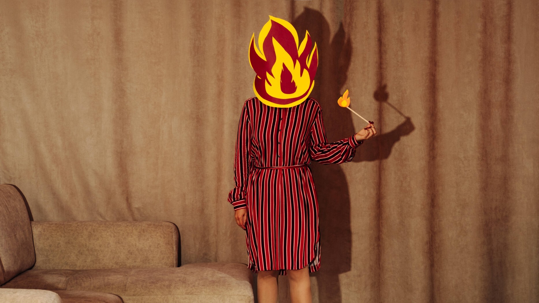 Eine Frau mit einer Flamme , die ihr Gesicht verdeckt und einem Streichholz, das entzündet ist.