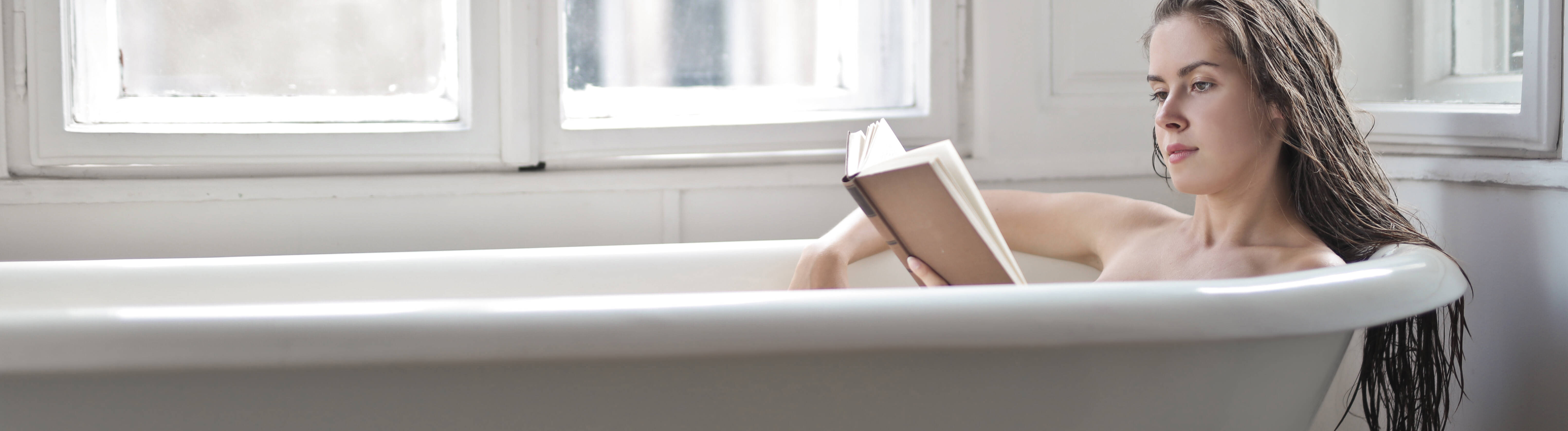 Eine Frau mit Buch in einer Badewanne.