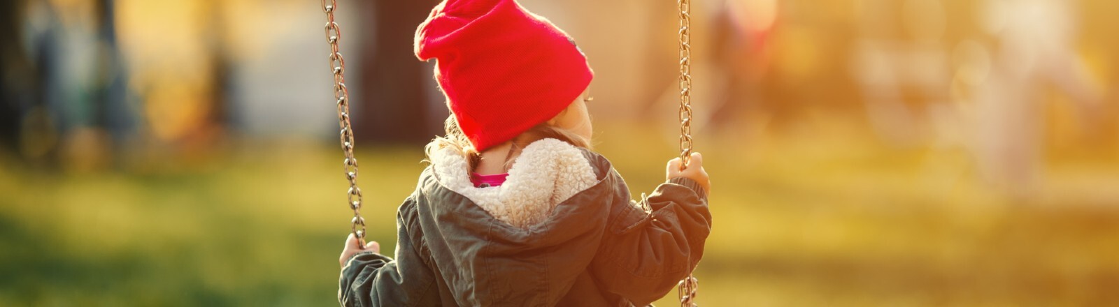 Kleines Kind auf einer Schaukel, Rückenansicht.