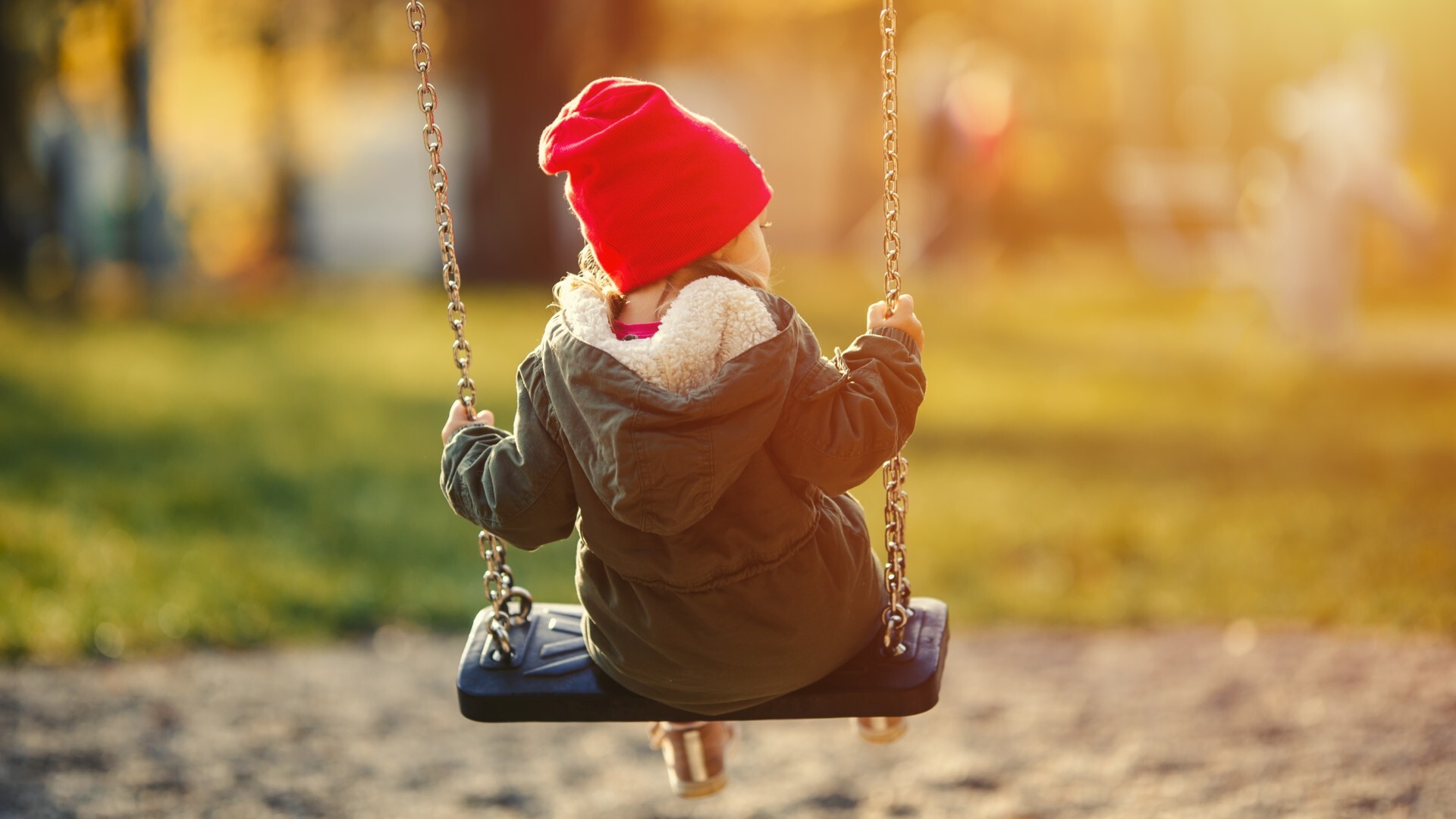 Kleines Kind auf einer Schaukel, Rückenansicht.