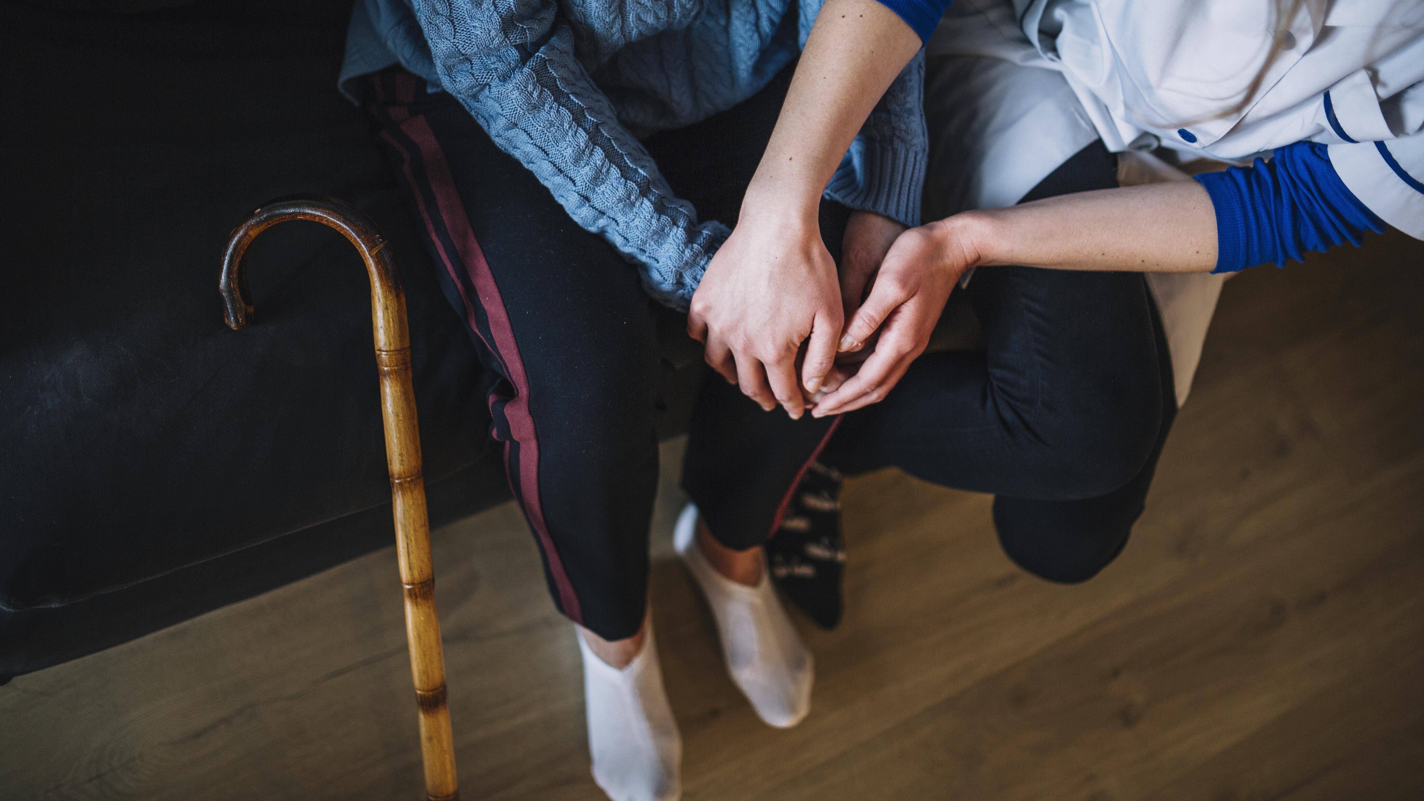 Symbolbild Pflege Eine Krankenschwester hält die Hände einer älteren Frau.