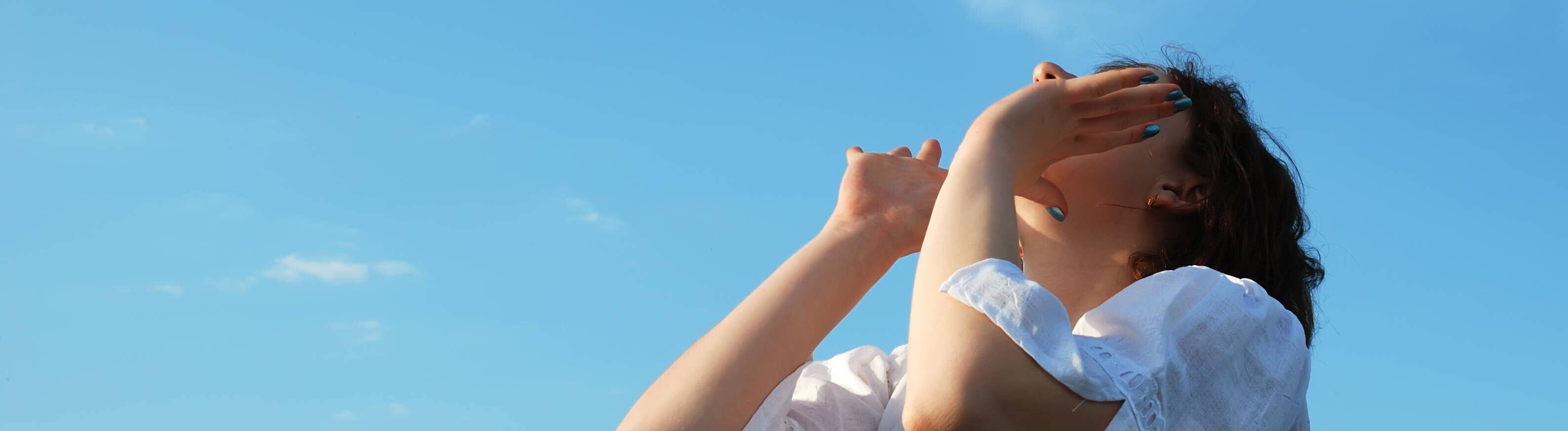 Eine Frau hält ihre Hände an den Mund und schreit in die Luft. Über ihr ist ein blauer Himmel.