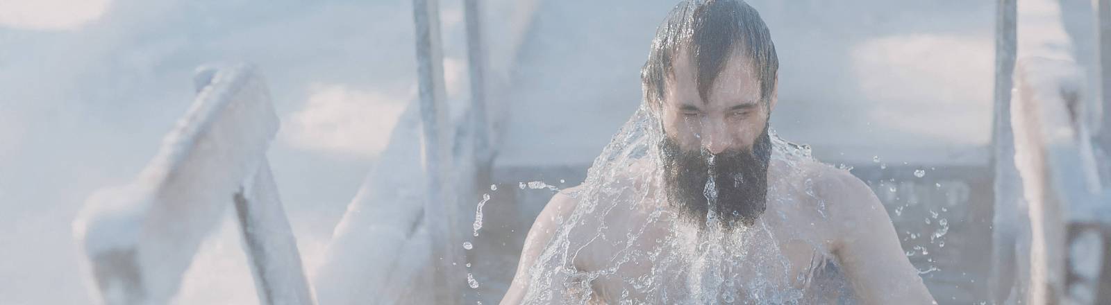 Person mit schwarzen Haaren und Bad taucht aus dem Eisbad auf