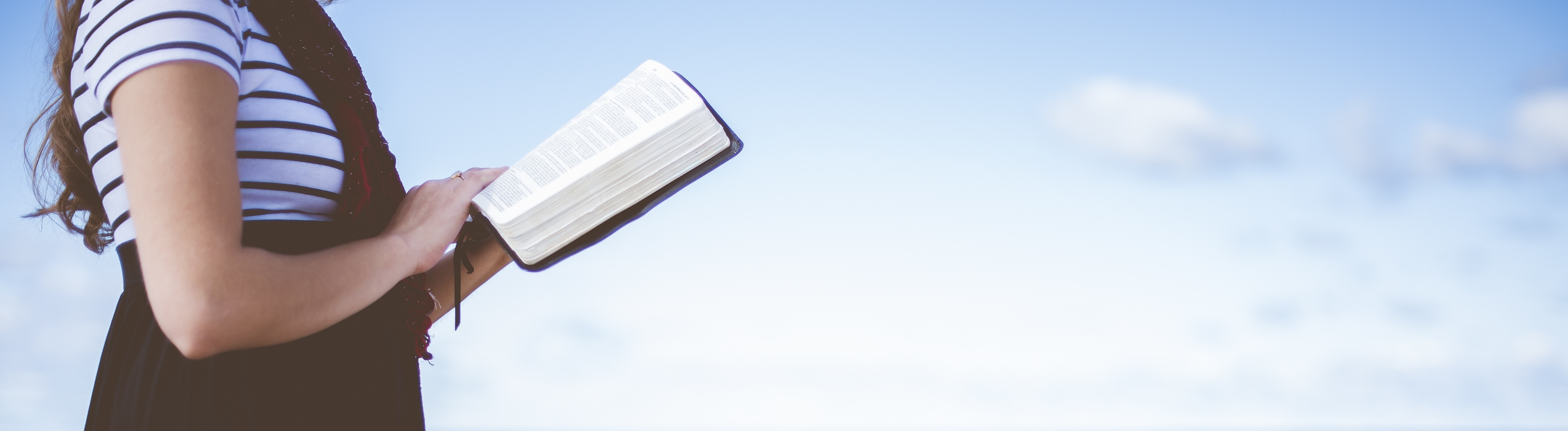 Eine Frau liest gehend ein Buch am Strand.