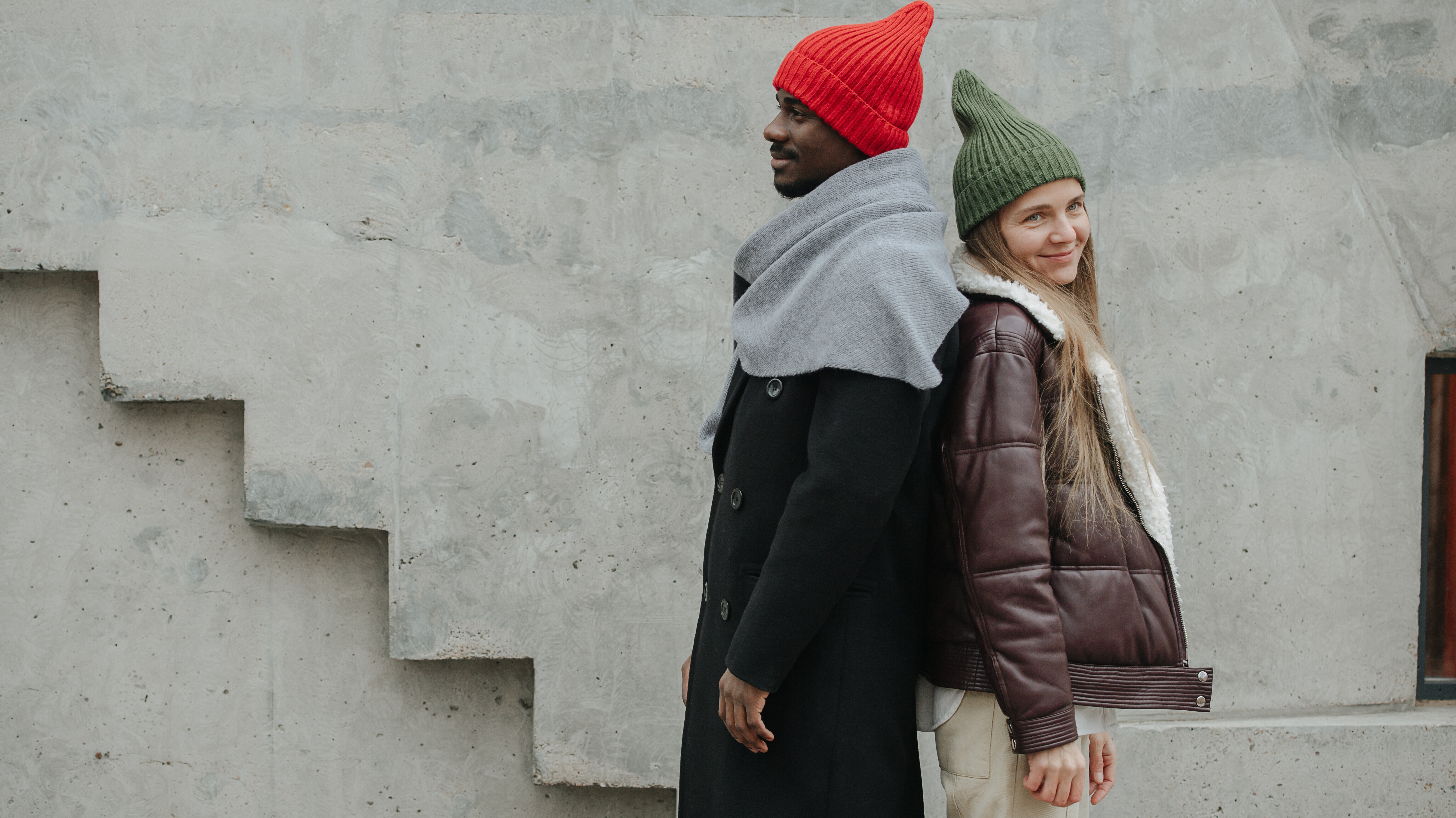 Ein Mann und eine Frau stehen Rücken an Rücken an einer Betonwand