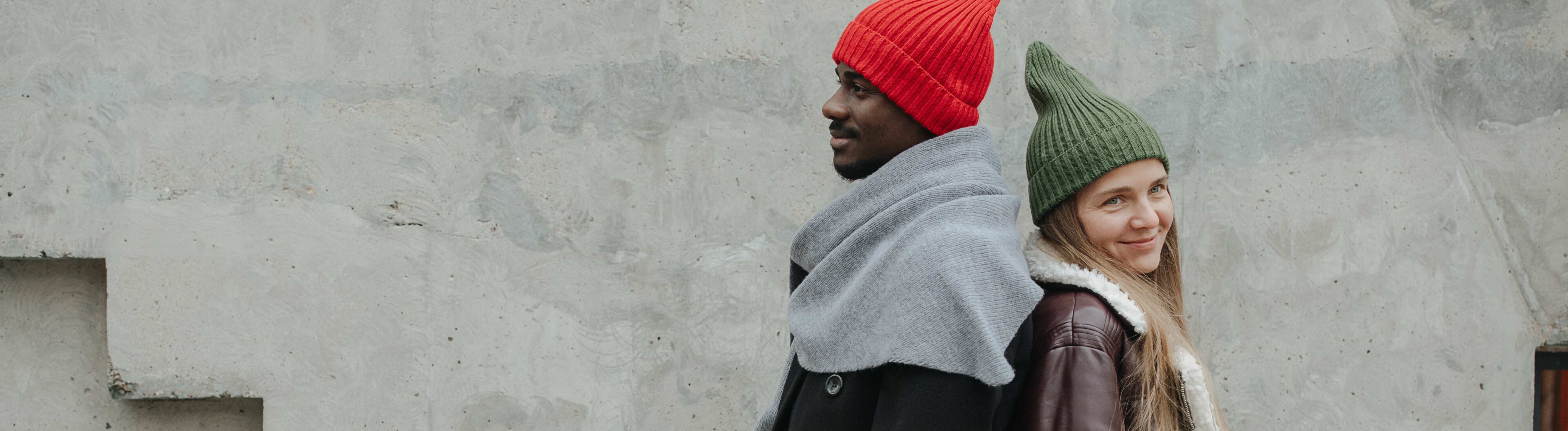 Ein Mann und eine Frau stehen Rücken an Rücken vor einer Betonwand