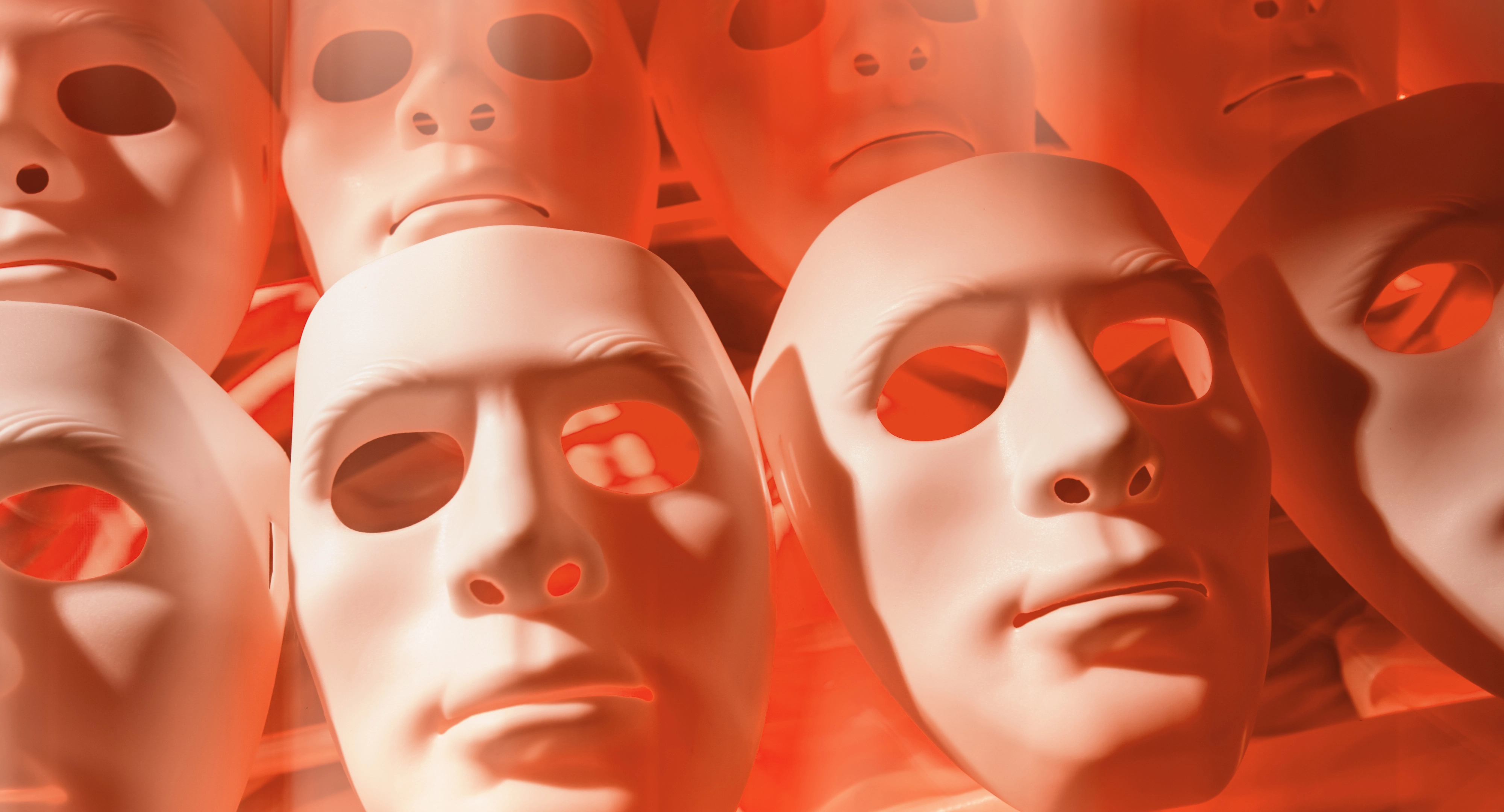 Weiße menschliche Masken werden von hinten rot beleuchtet