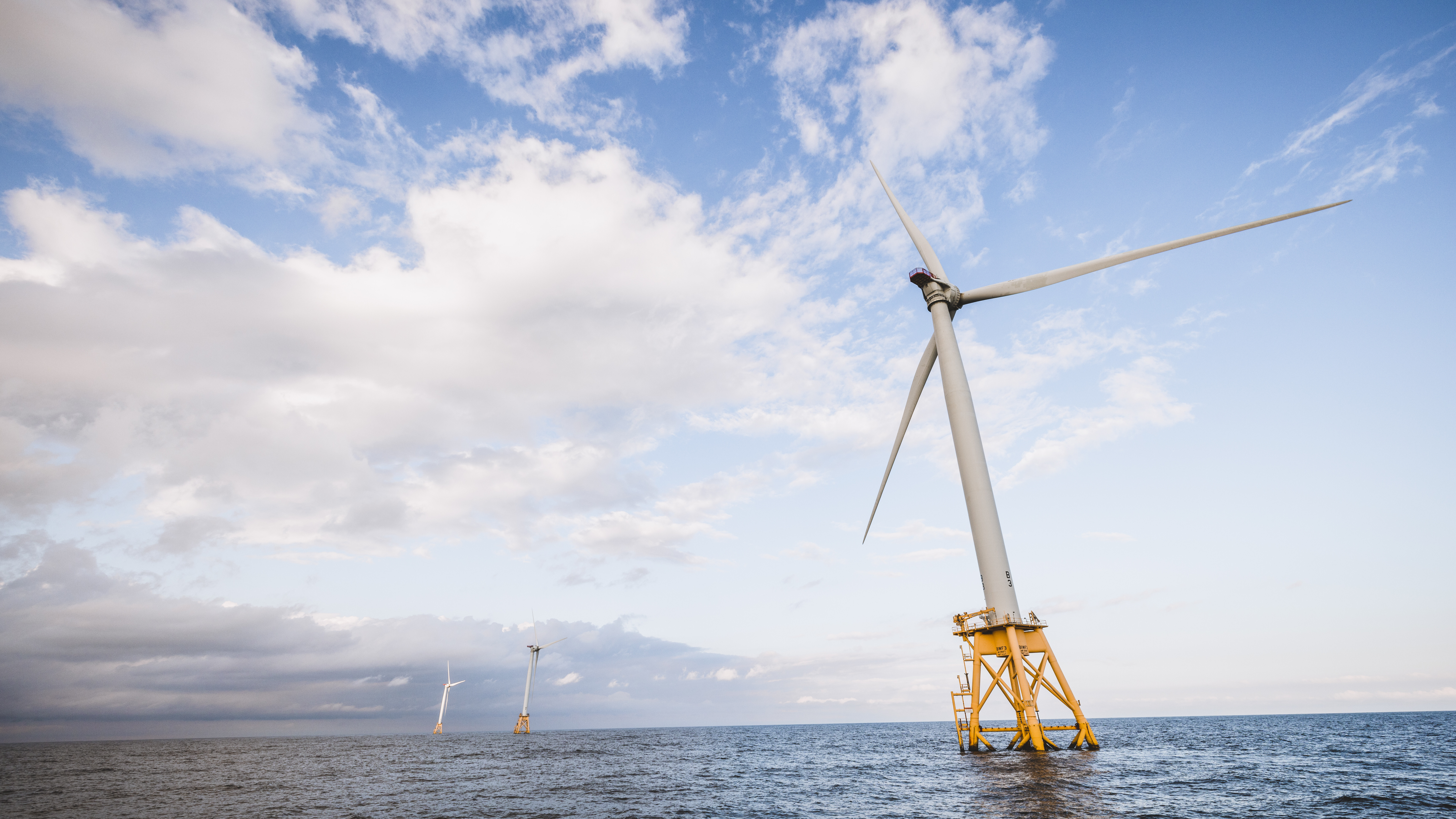 Eine Offshore-Windkraftanlage im US-Bundesstaat Rhode Island steht auf gelben Pfeilern schräg im Meer.