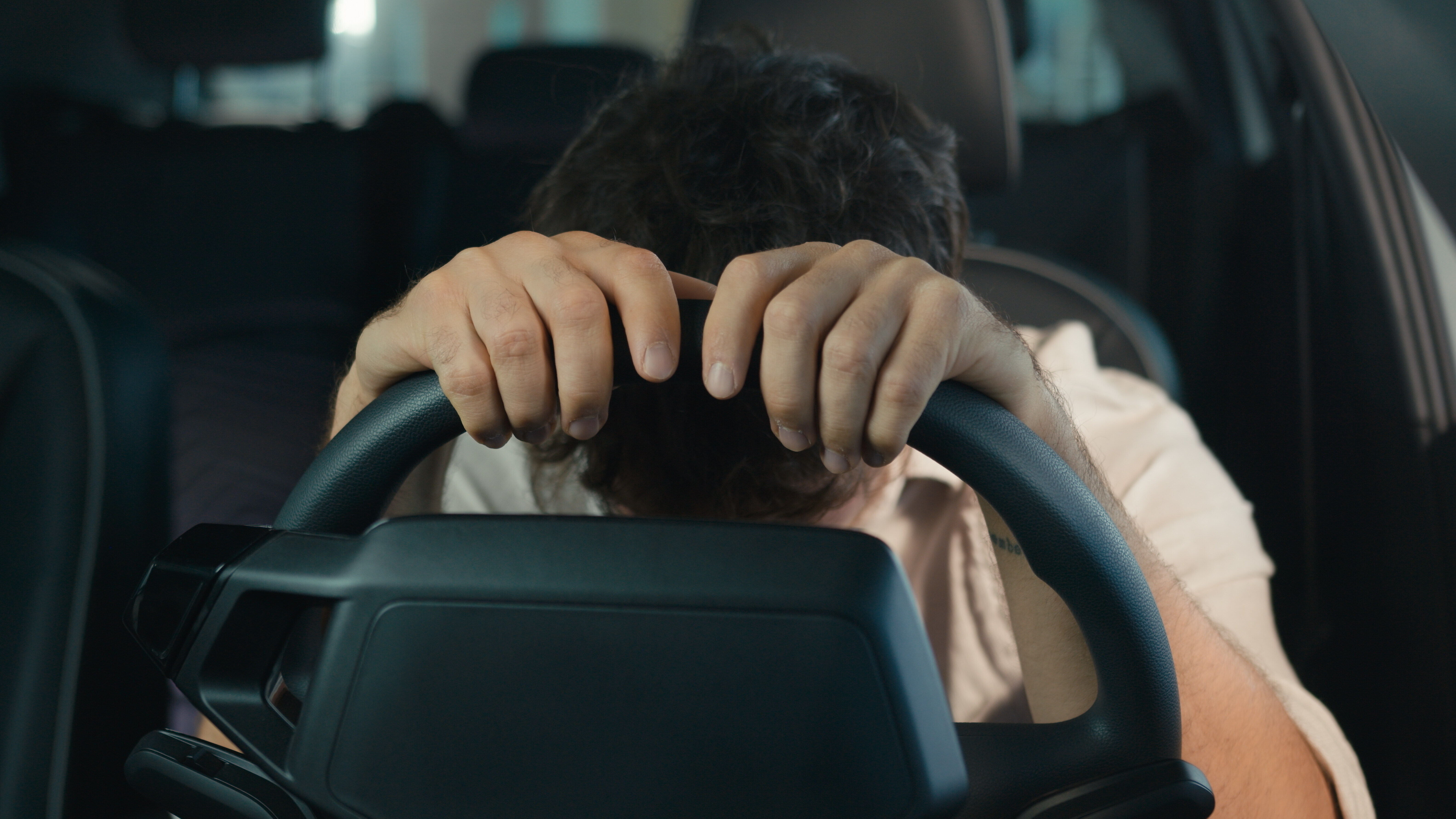 Ein Mann sitzt verzweifelt hinter dem Steuer seines Autos und lässt den Kopf hängen