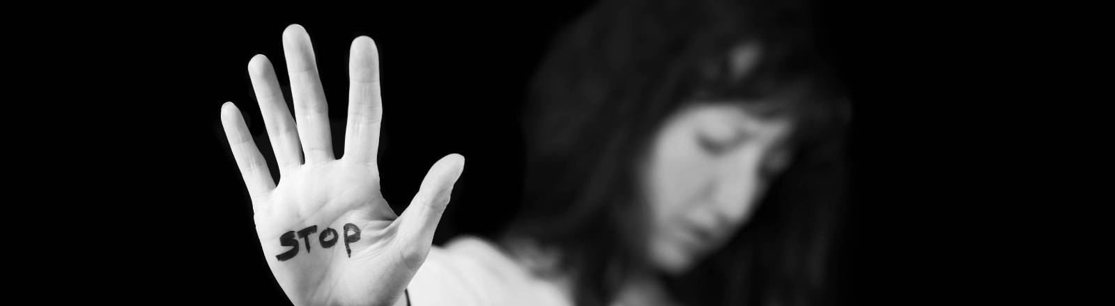 Frau streckt ihre Handfläche aus, auf der Stopp steht