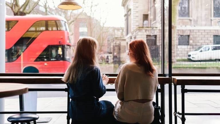 Zwei Frauen sitzen in einem Café nebeneinander