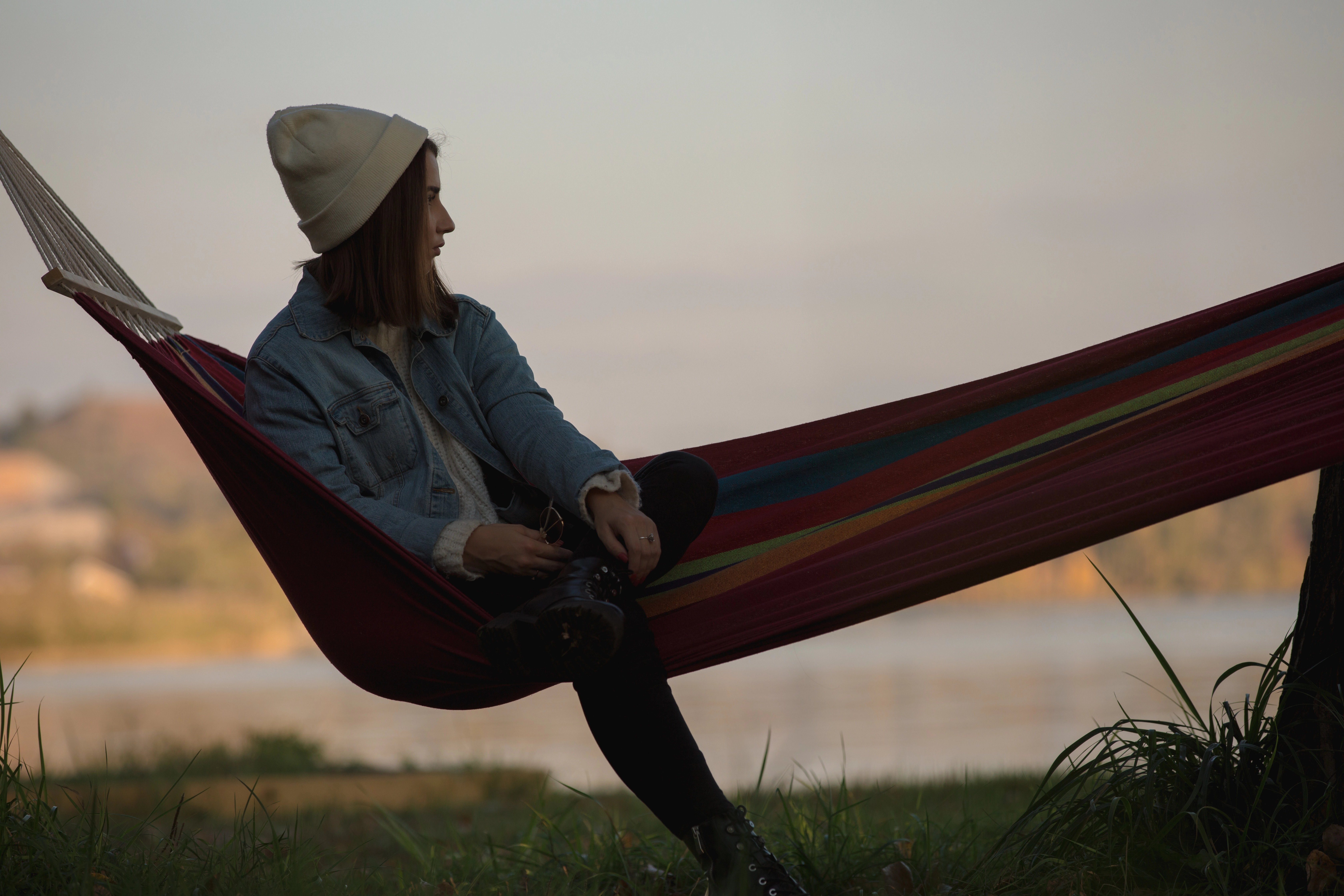 Eine Frau chillt auf einer Hängematte in der Abendsonne. Sie wirkt nachdenklich.