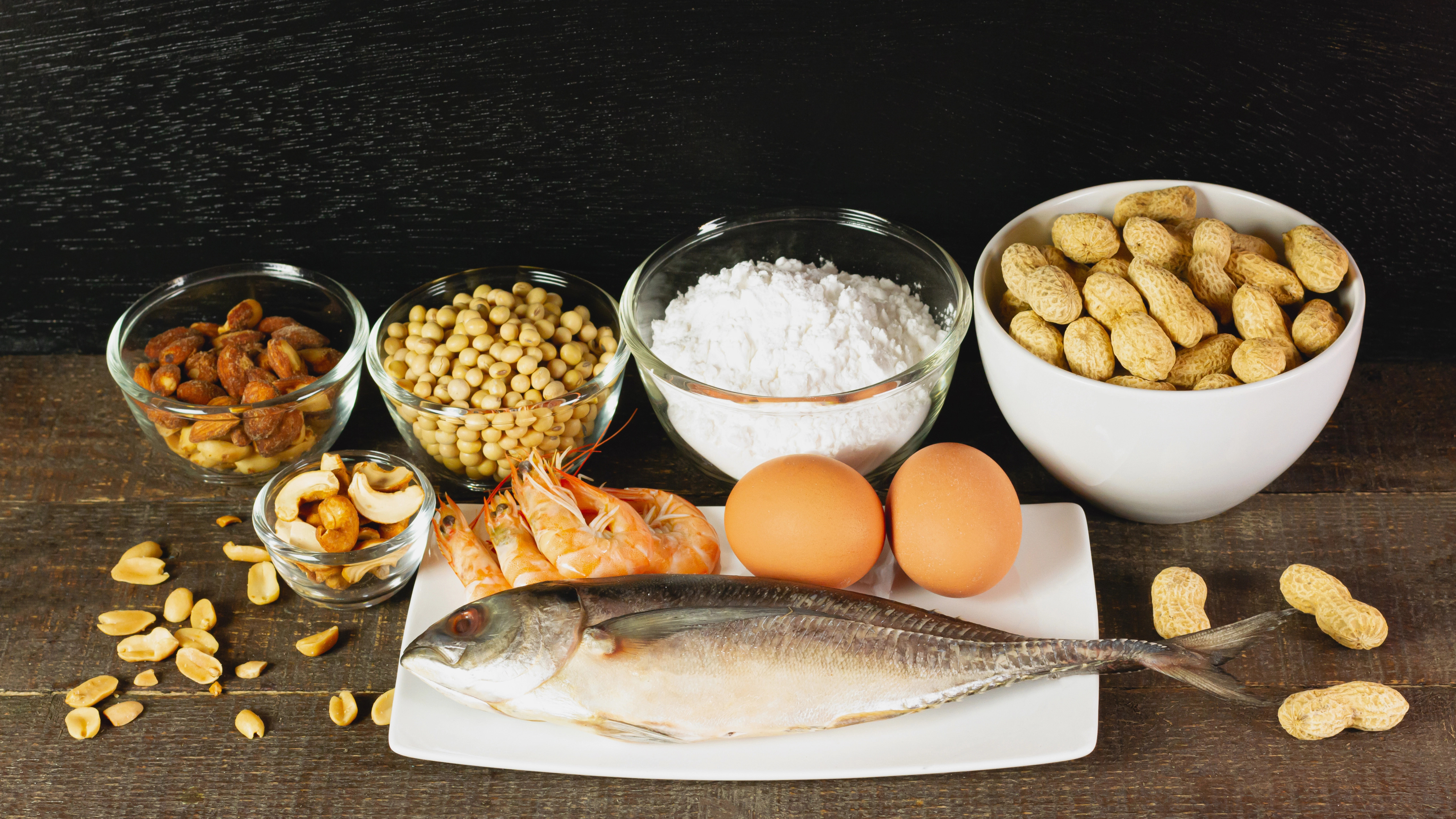 Zu den Hauptallergenen zählen: Fisch, Erdnüsse, Mandeln, Milch, Weizenmehl, Soja, Eier, Cashewkerne und Meeresfrüchte. Hier auf einem rustikalen Tisch.