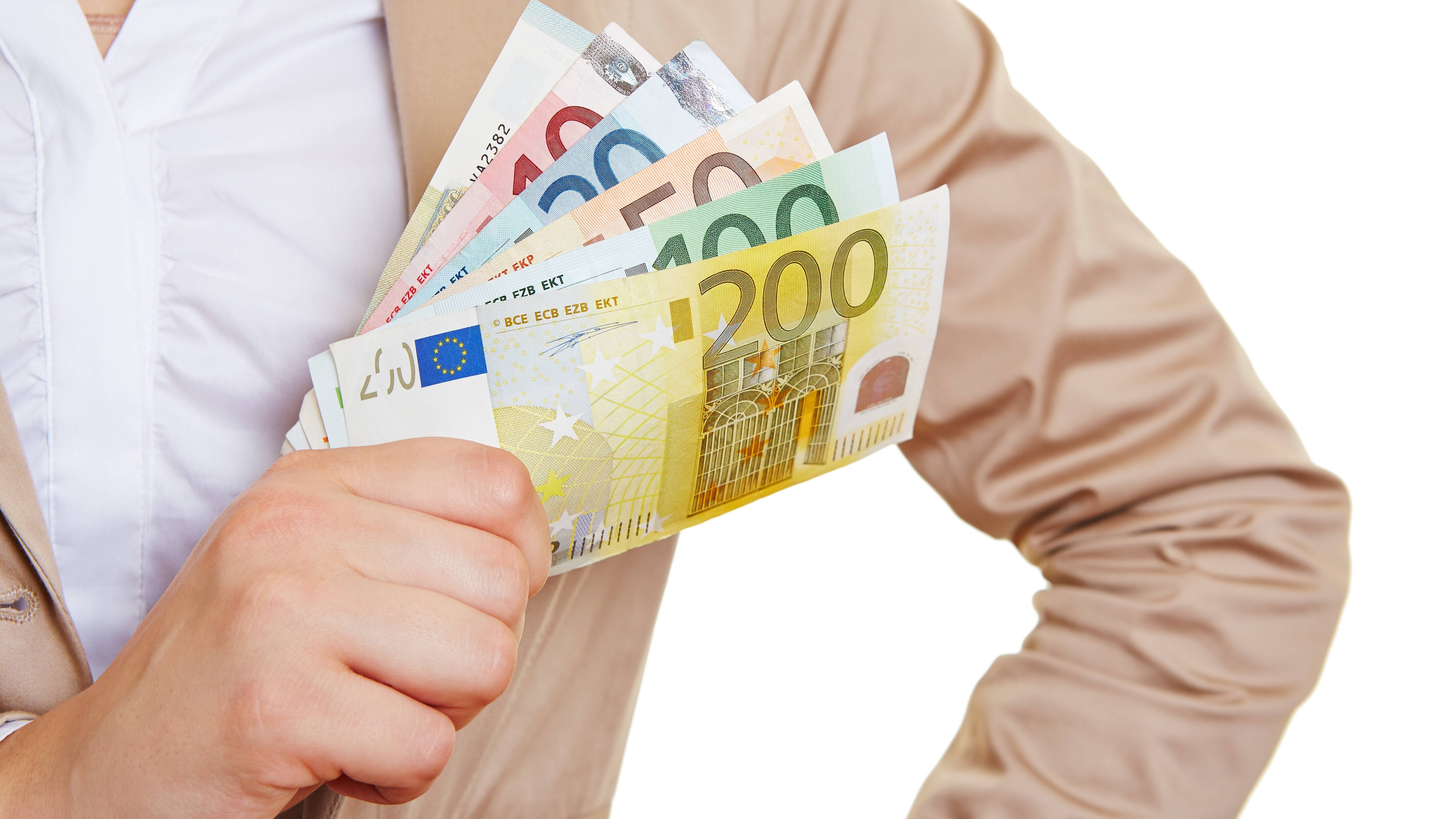 Eine Frau hält aufgefächerte Euro-Geldscheine in ihrer Hand