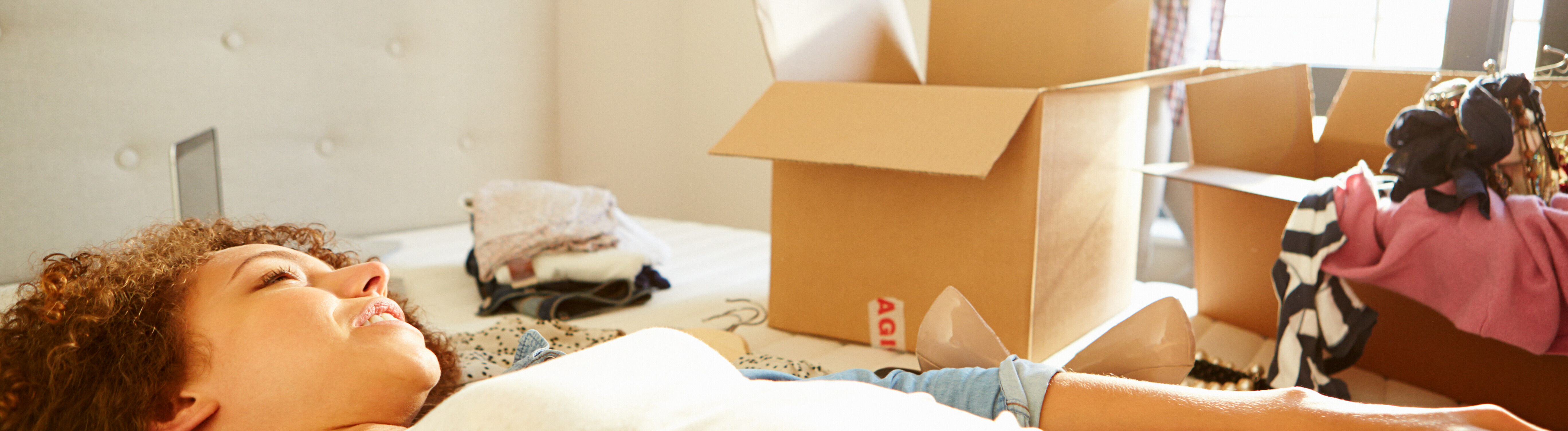 Frauen mit Kisten im Schlafzimmer beim Einzug in ein neues Zuhause.