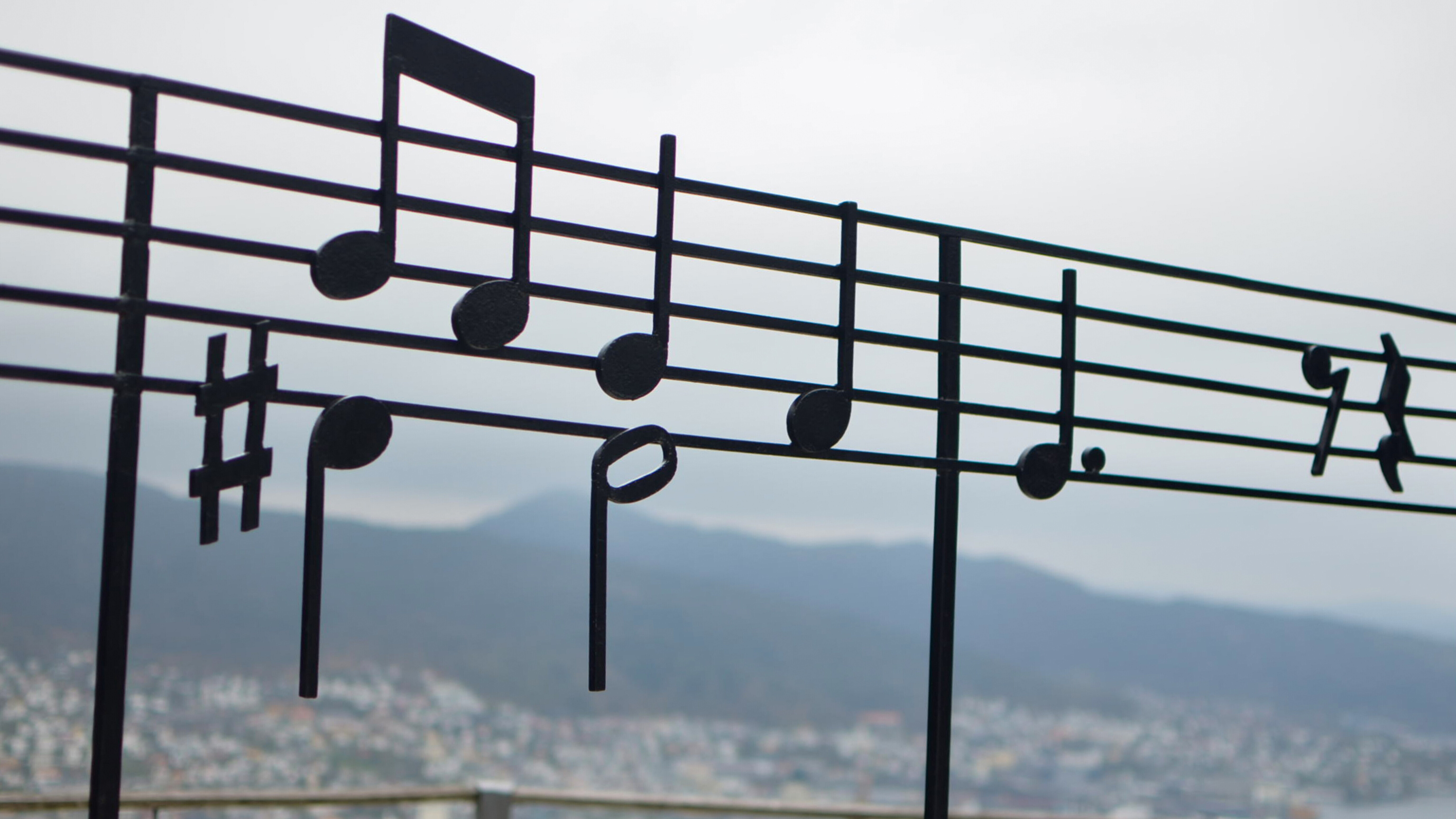 Musikalische Noten im Kontrast zur Landschaft von Bergen auf dem Berg Fløyen in Norwegen.