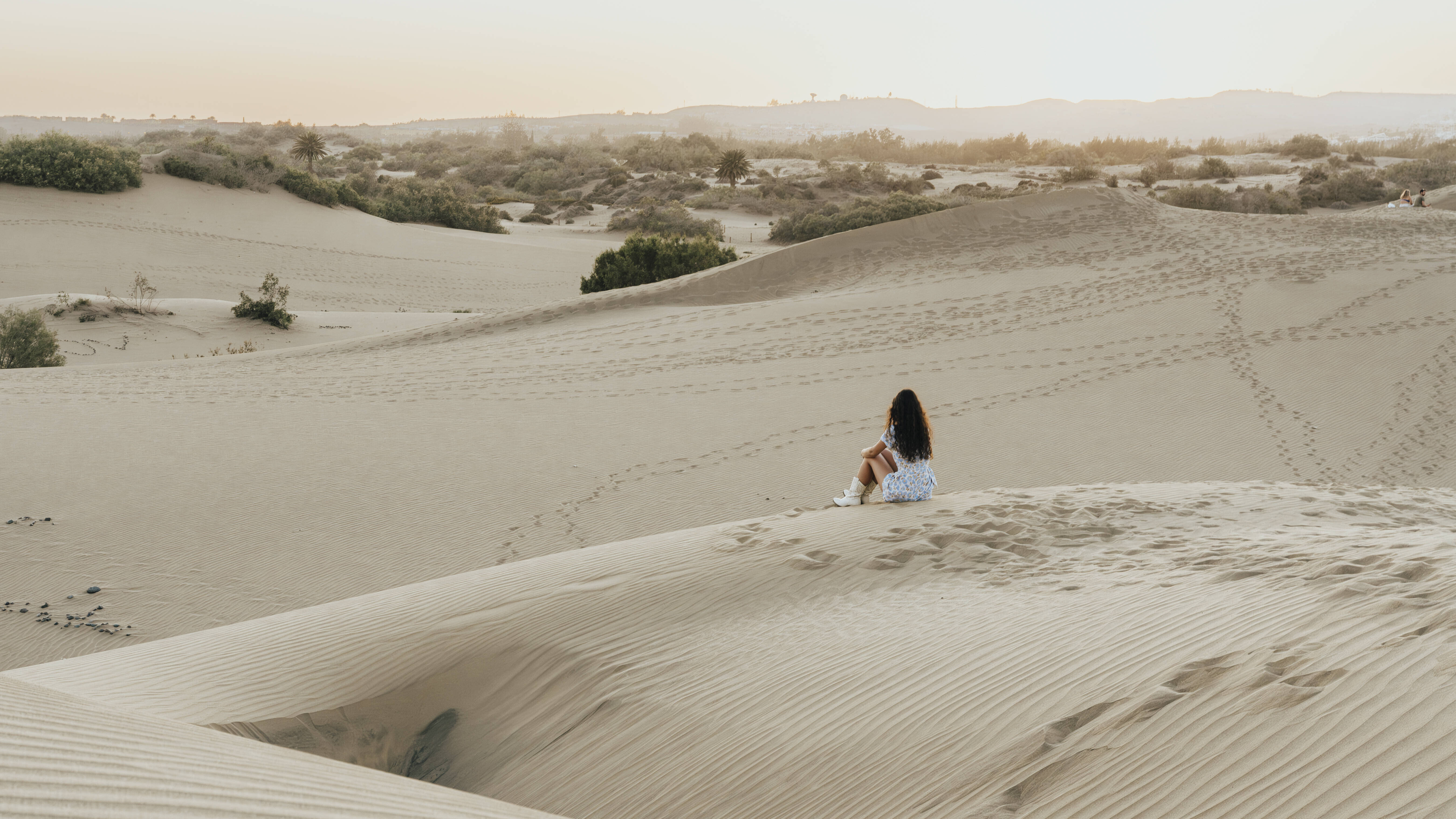 Eine Frau sitzt alleine auf einer Sanddüne in der Wüste
