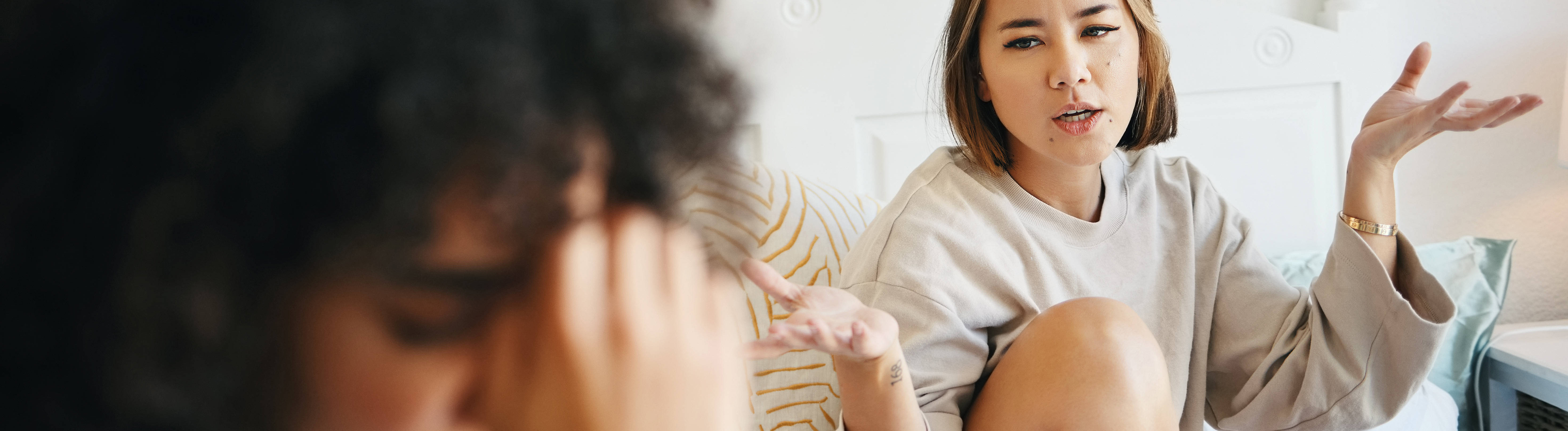 Zwei Frauen diskutieren. Die eine stützt die Stirn in die Hand.
