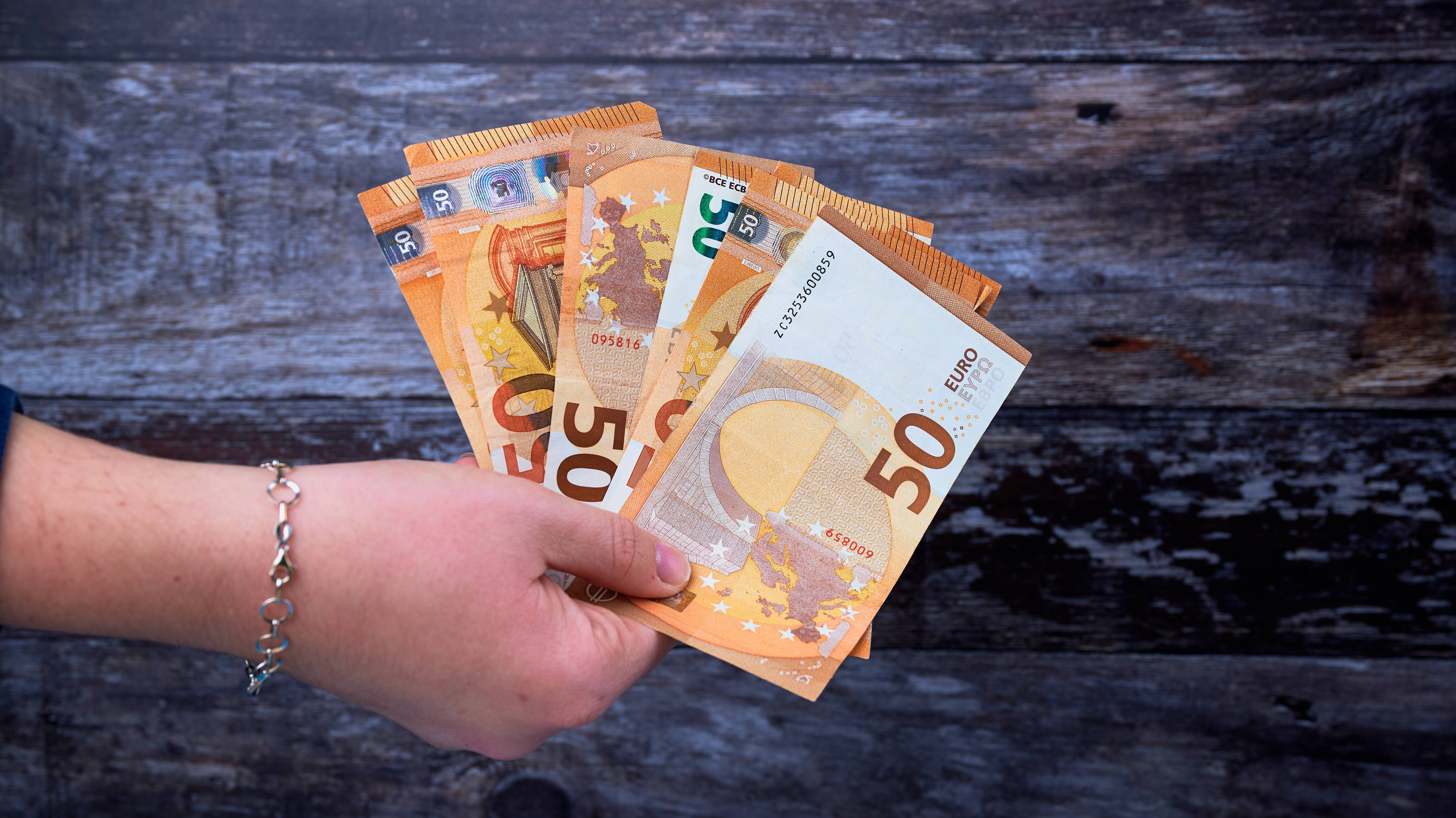 Eine Hand hält 50-Euro-Scheine.