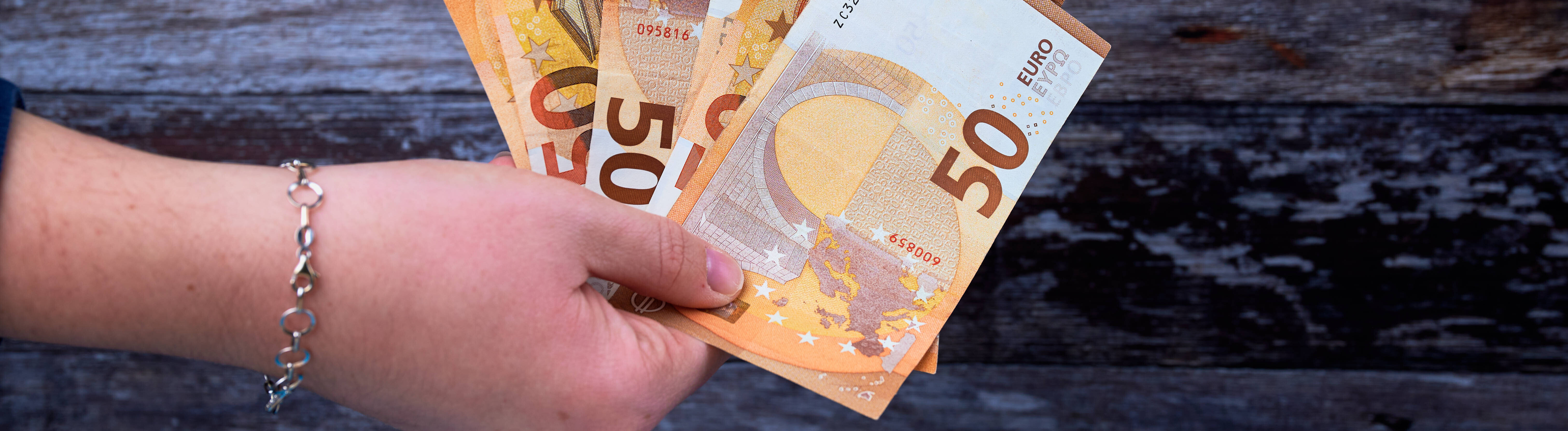 Eine Hand hält 50-Euro-Scheine