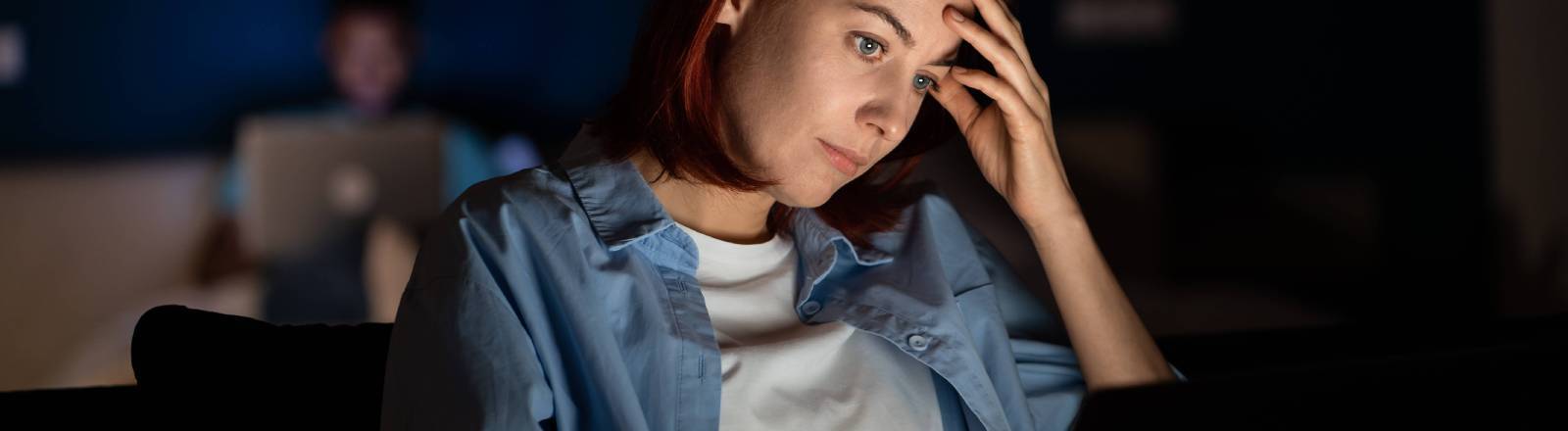 Eine Frau sitzt abends vor dem Laptop