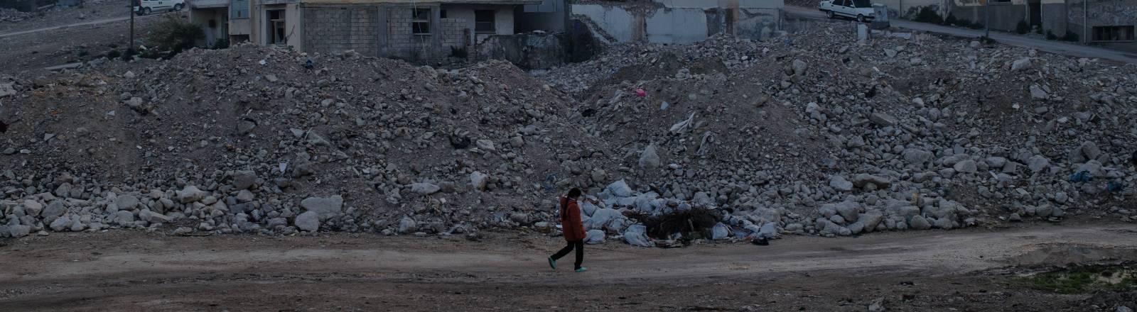 Ein Mädchen geht in der türkischen Stadt Hatay an Schutt und zerstörten Häusern entlang