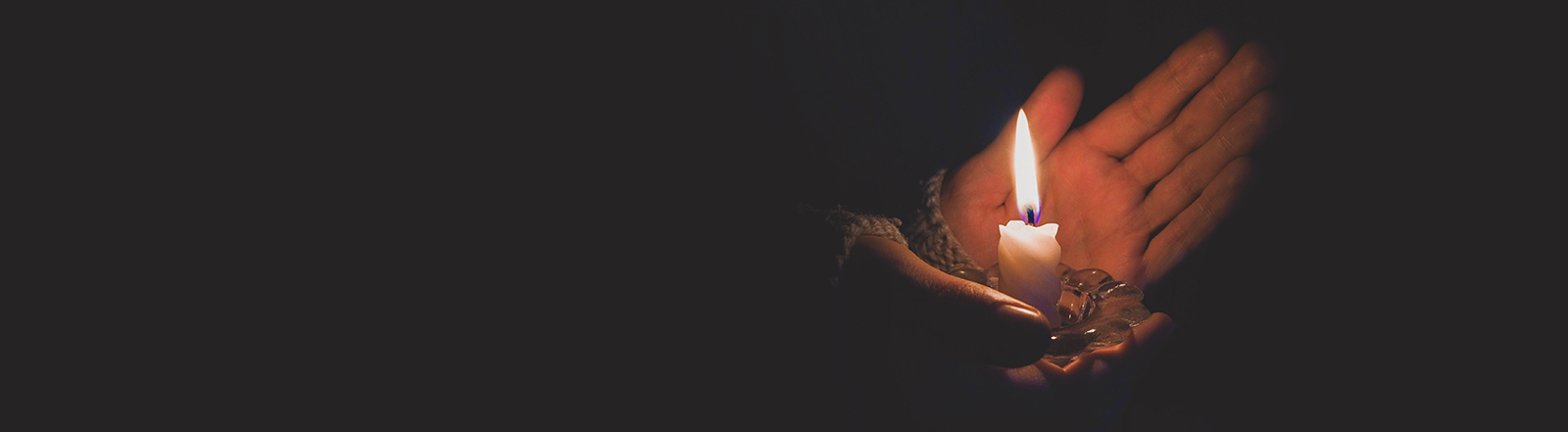 Foto einer brennende Kerze in weiblichen Händen bei Nacht