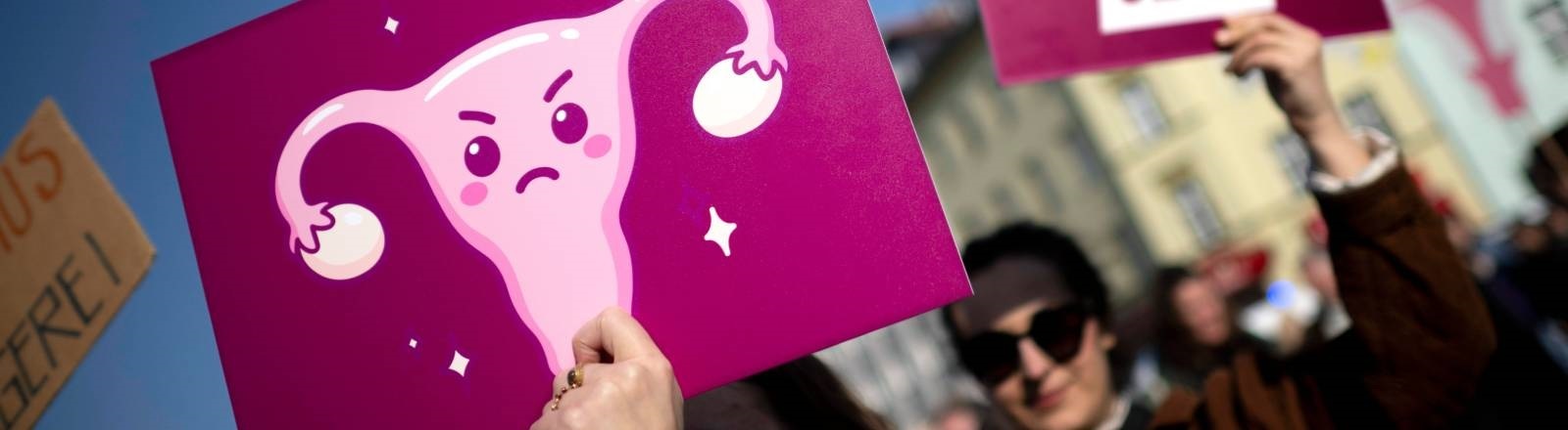 Während einer Demonstration in Berlin hält eine Frau ein Plakat mit der Abbildung einer Gebärmutter hoch
