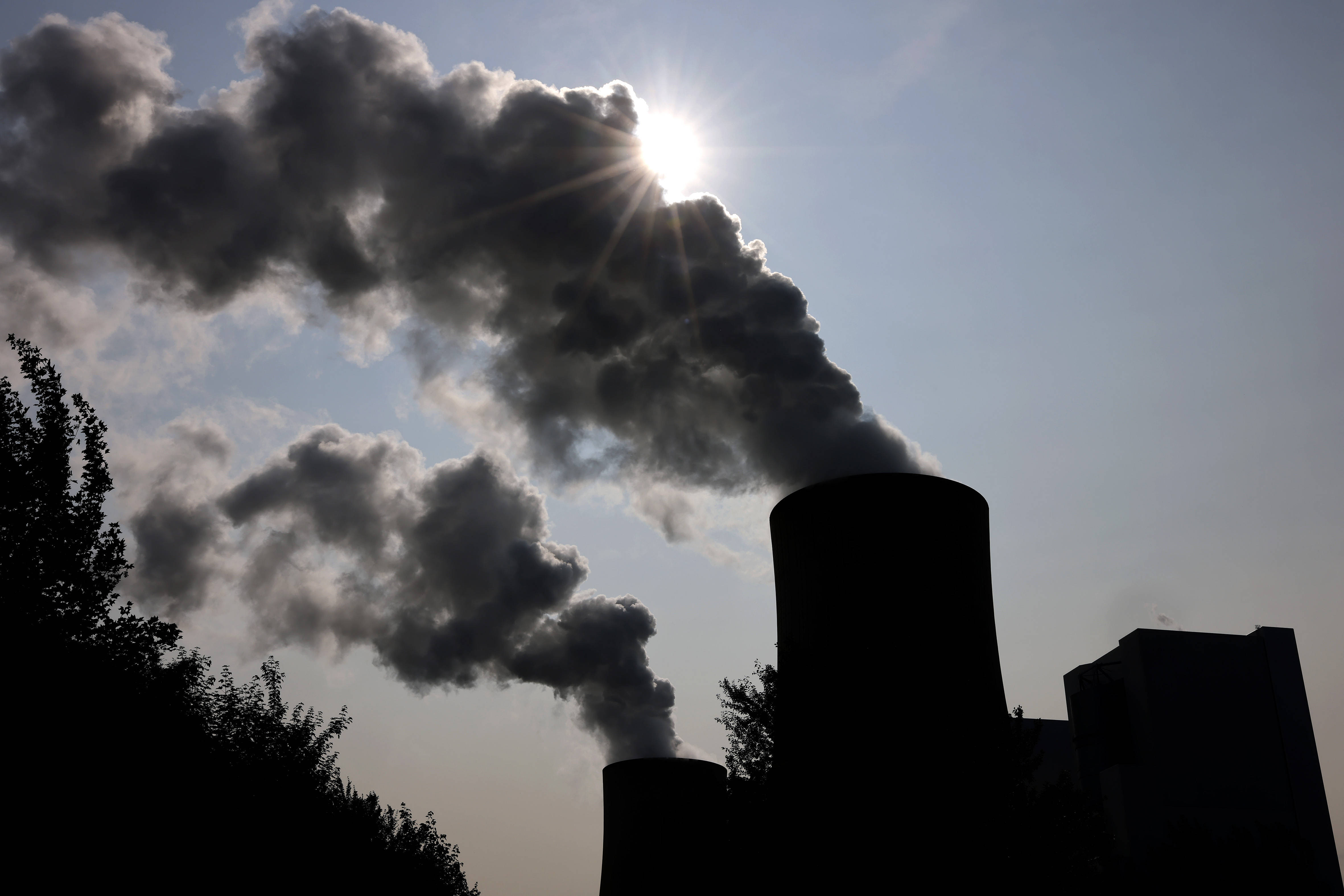 Das RWE-Kohlekraftwerk Neurath an einem sonnigen Vormittag. Die Sonne verschwindet hinter Emissionen aus den Kraftwerkstürmen.