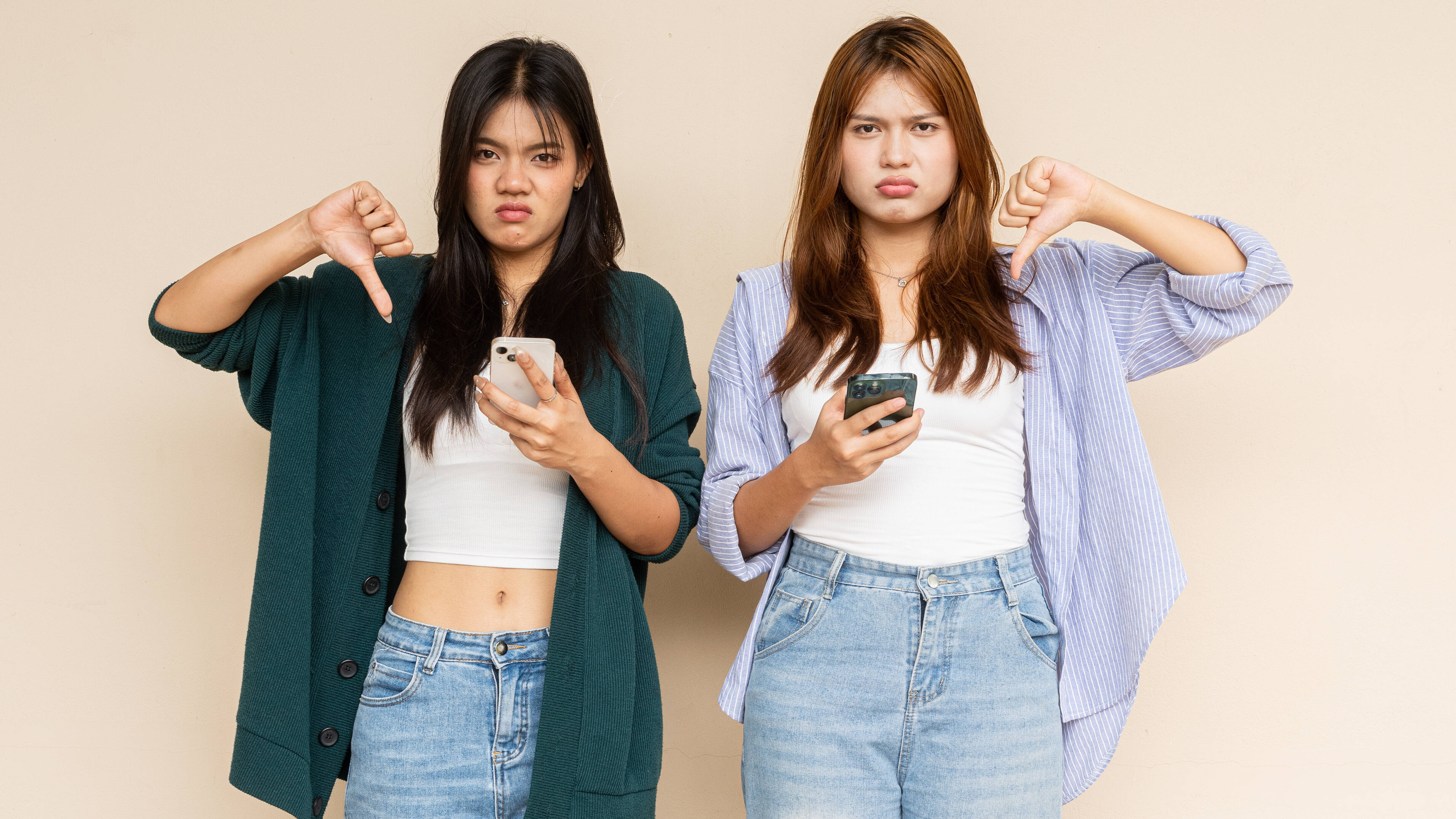 Zwei Frauen zeigen mit dem Daumen nach unten