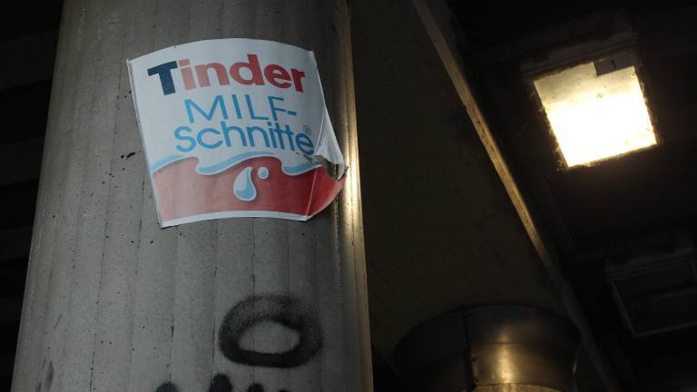 Aufkleber mit der Aufschrift Tinder MILF-Schnitte und dem Logo der Süßigkeit Milchschnitte klebt an einem Brückenpfeiler