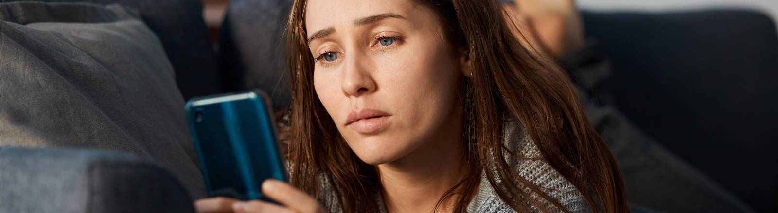 Eine junge Frau schaut besorgt auf ihr Smartphone