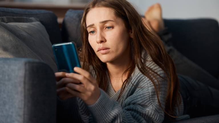 Eine junge Frau schaut besorgt auf ihr Smartphone