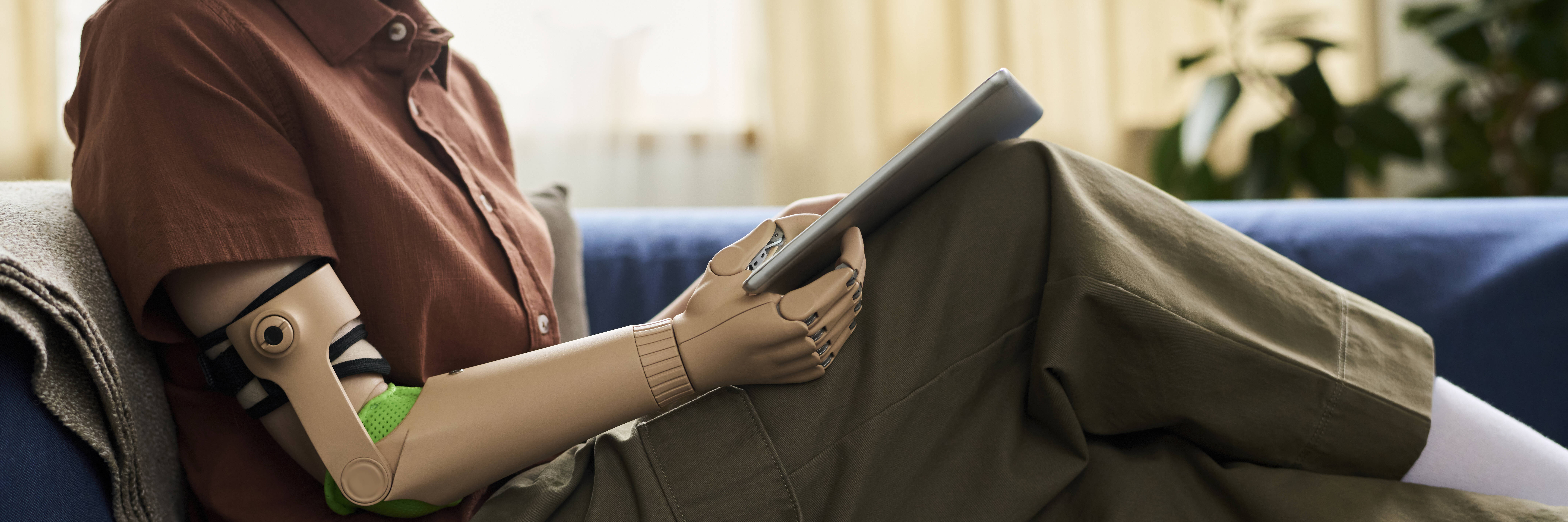 Mädchen mit Armprothese, das ein Tablet benutzt, Symbolfoto.