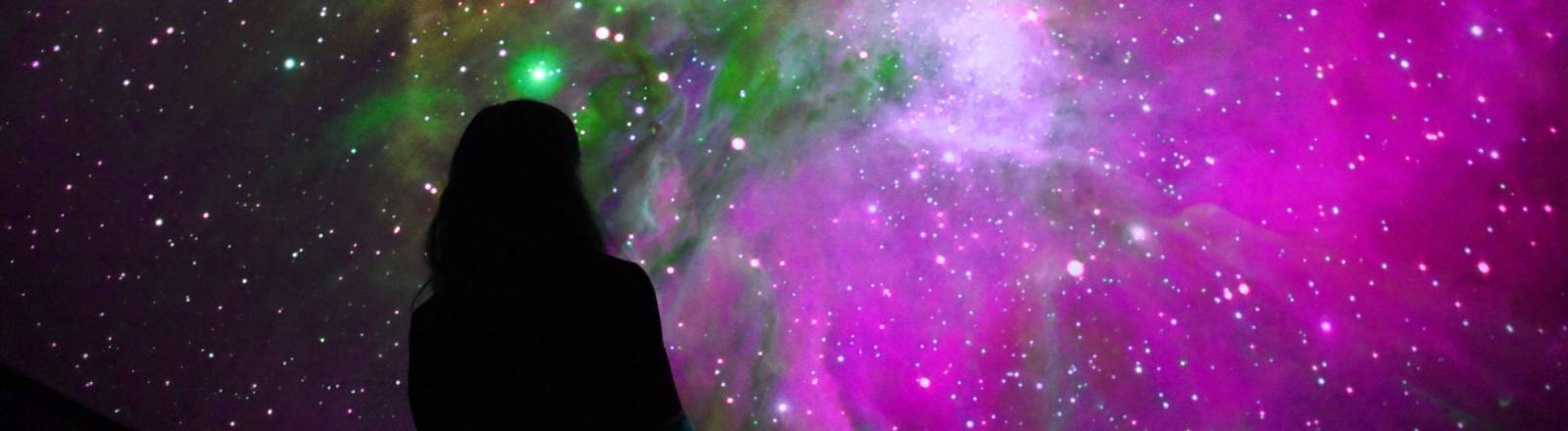 Eine Person betrachtet den Sternenhimmel in einem Planetarium
