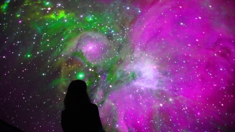 Eine Person betrachtet den Sternenhimmel in einem Planetarium