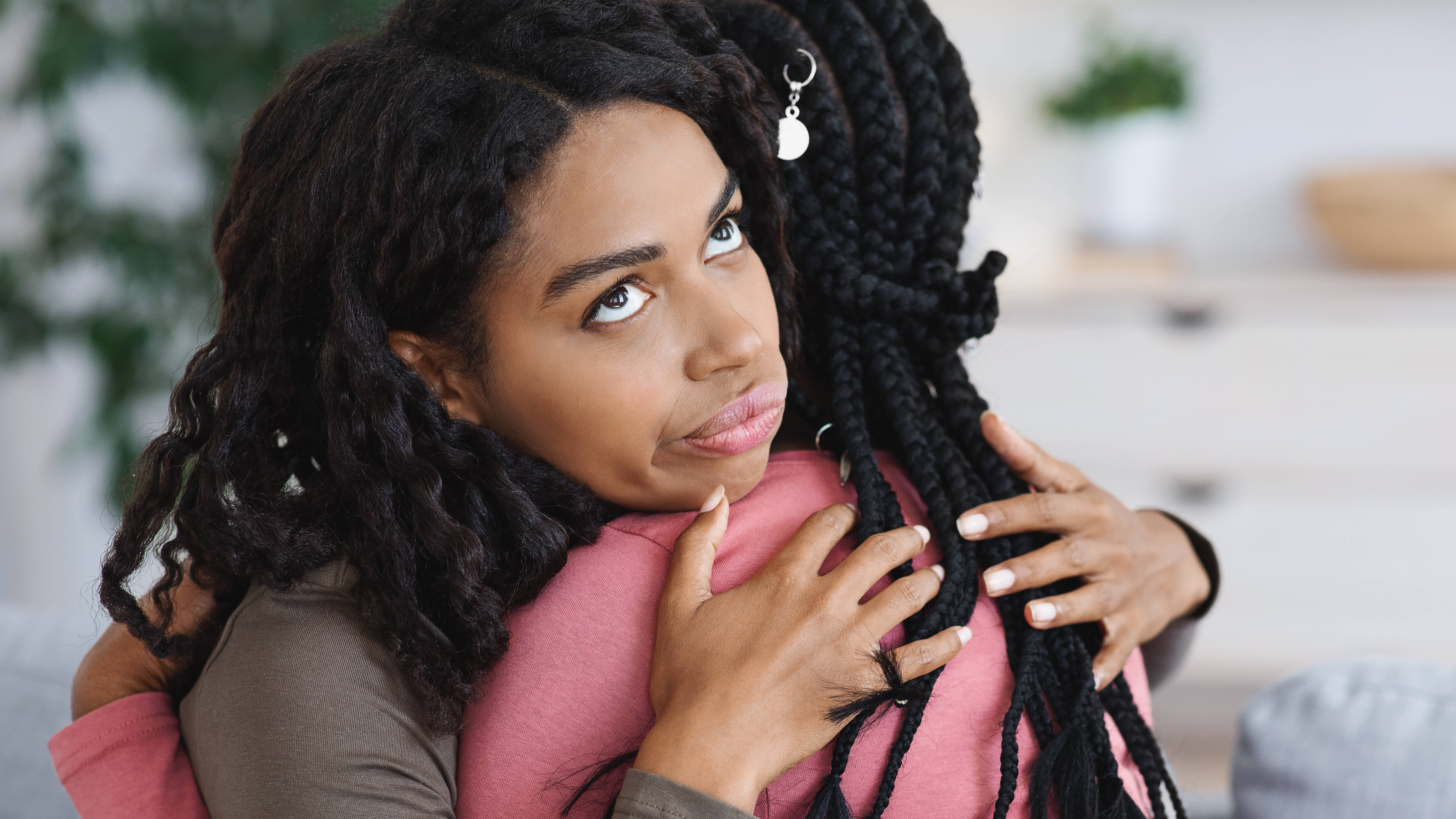 Junge Frau rollt mit den Augen während sie eine Freundin umarmt.