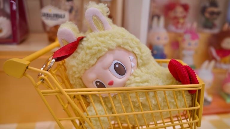 Eine Labubu-Plüschfigur liegt in einem Einkaufswagen