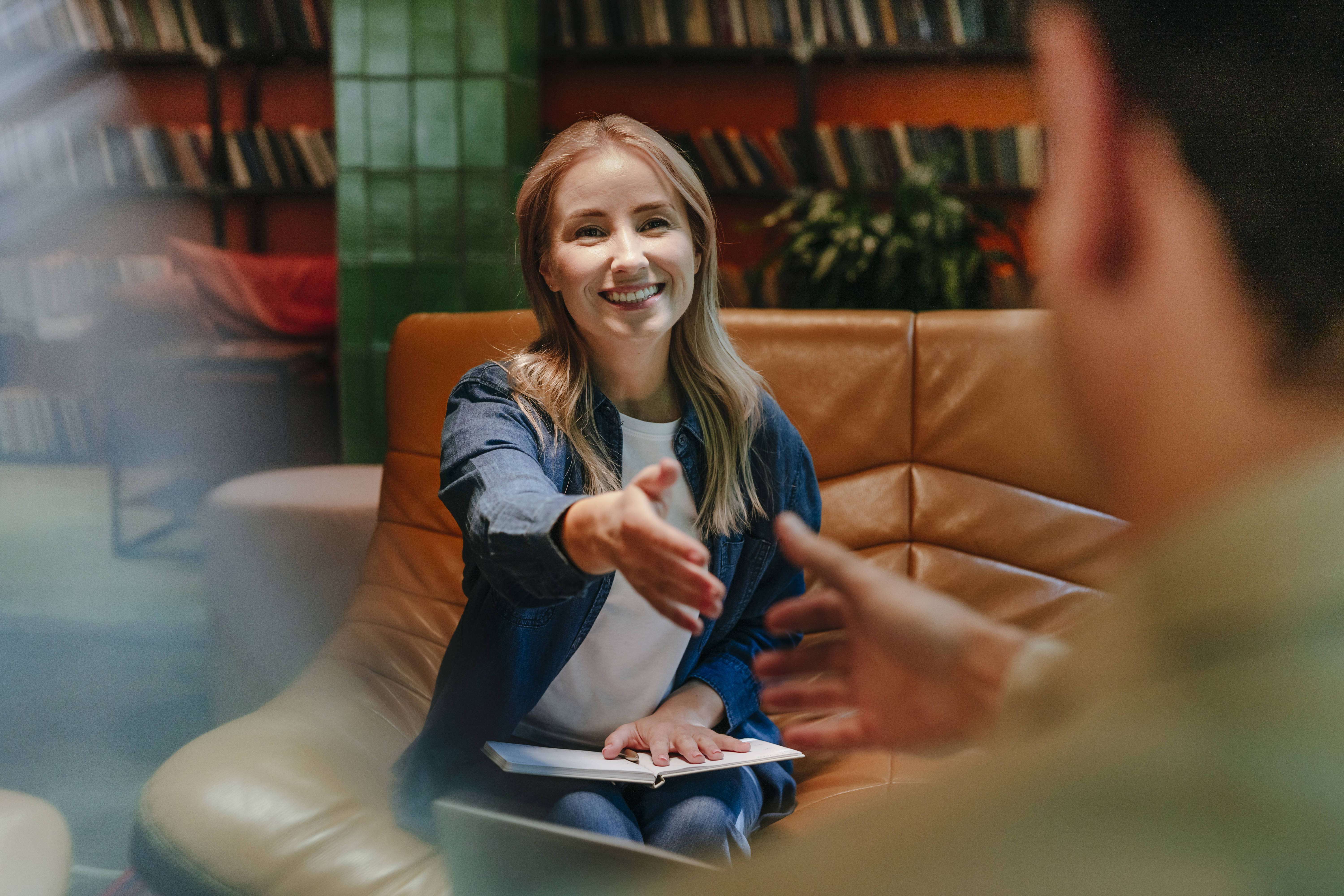 Frau gibt jungem Mann nach Bewerbungsggespräch die Hand