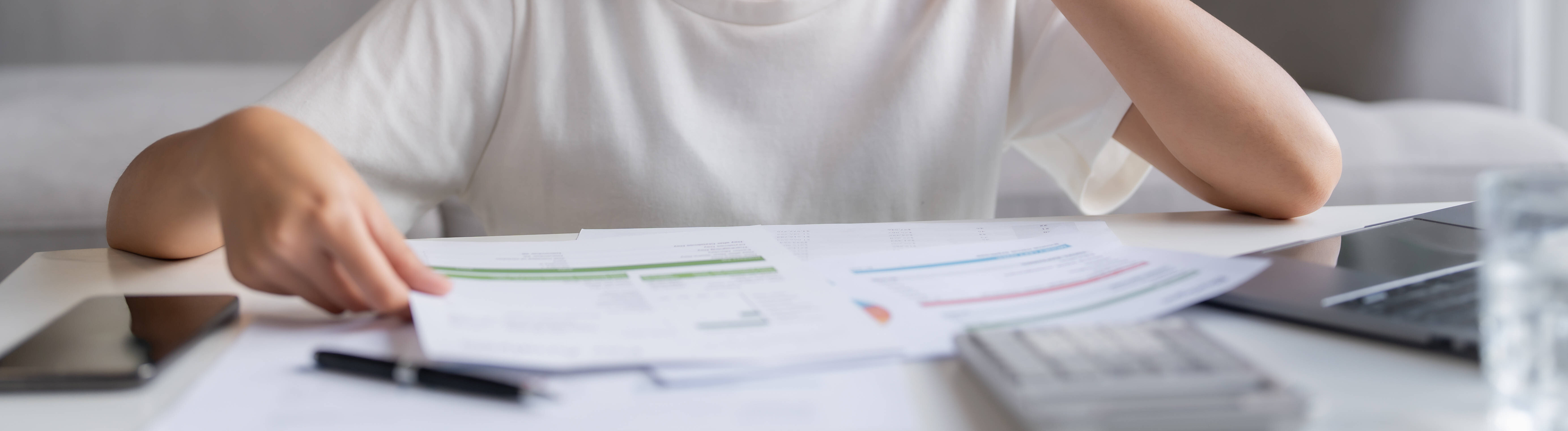 Frau blickt konzentriert auf Unterlagen, die vor ihr auf einem Tisch liegen