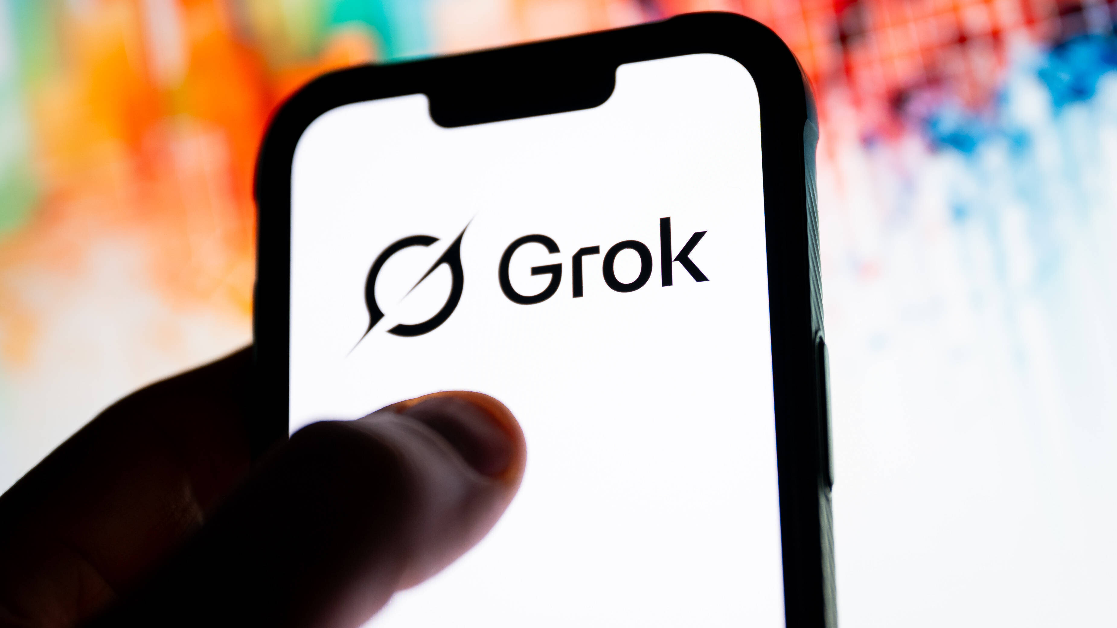 Daumen auf Smartphone-Screen, auf dem "Grok" steht