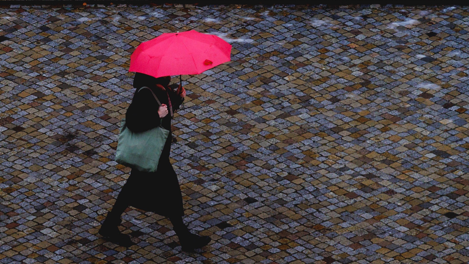 Eine Frau laeuft mit einem Regenschirm nahe des Humboldt-Forums in Berlin
