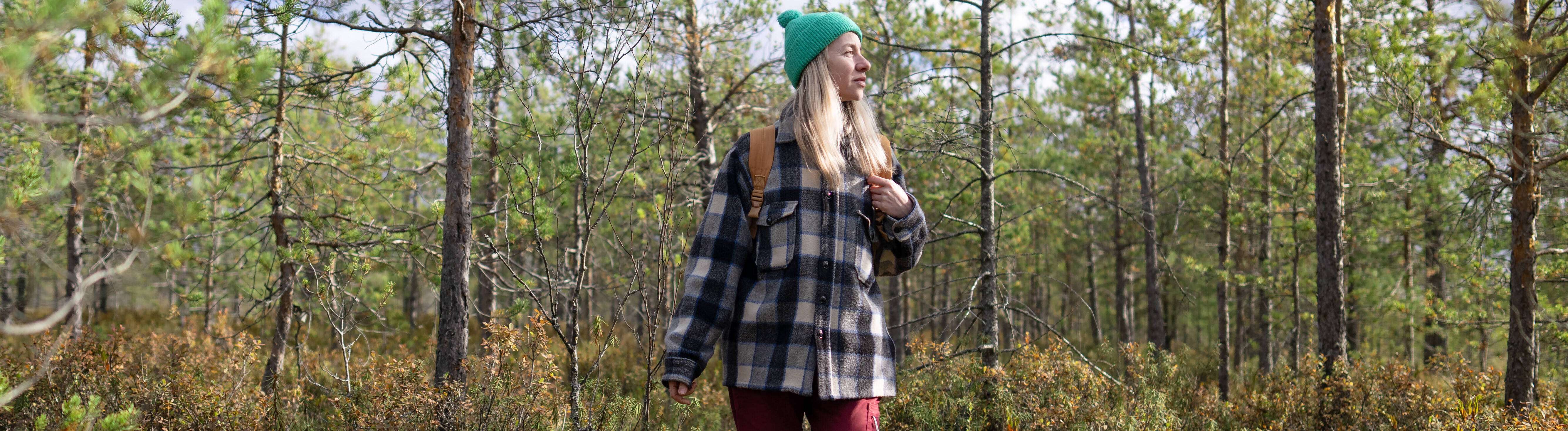 Eine Frau läuft in Wanderkleidung durch einen Wald.