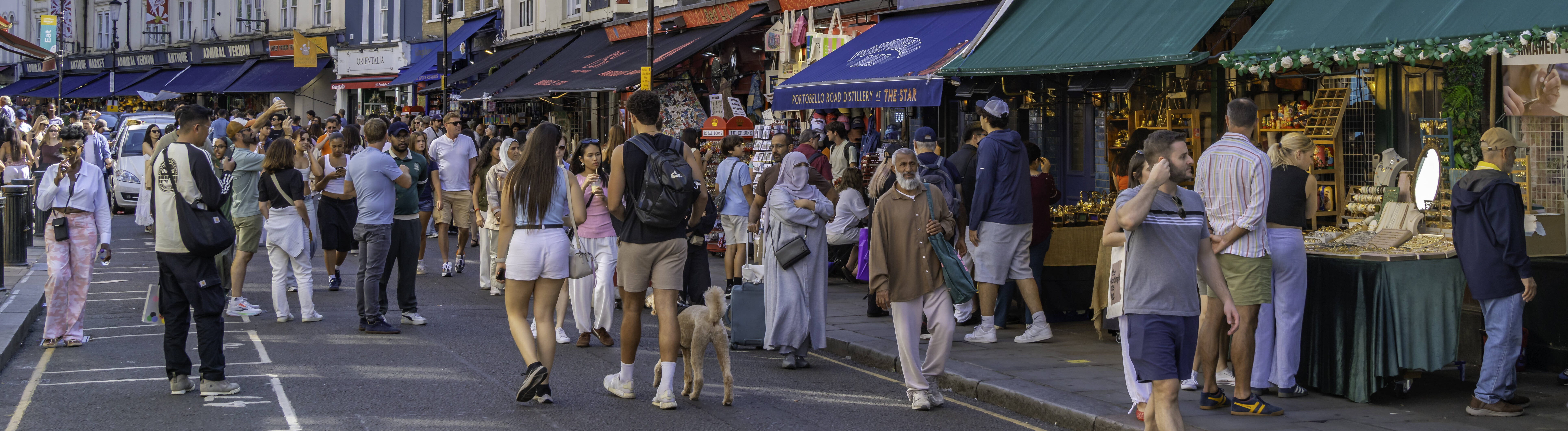 An einem sonnigen Tag im Sommer schlendern Menschen durch die Portobello Road in London.