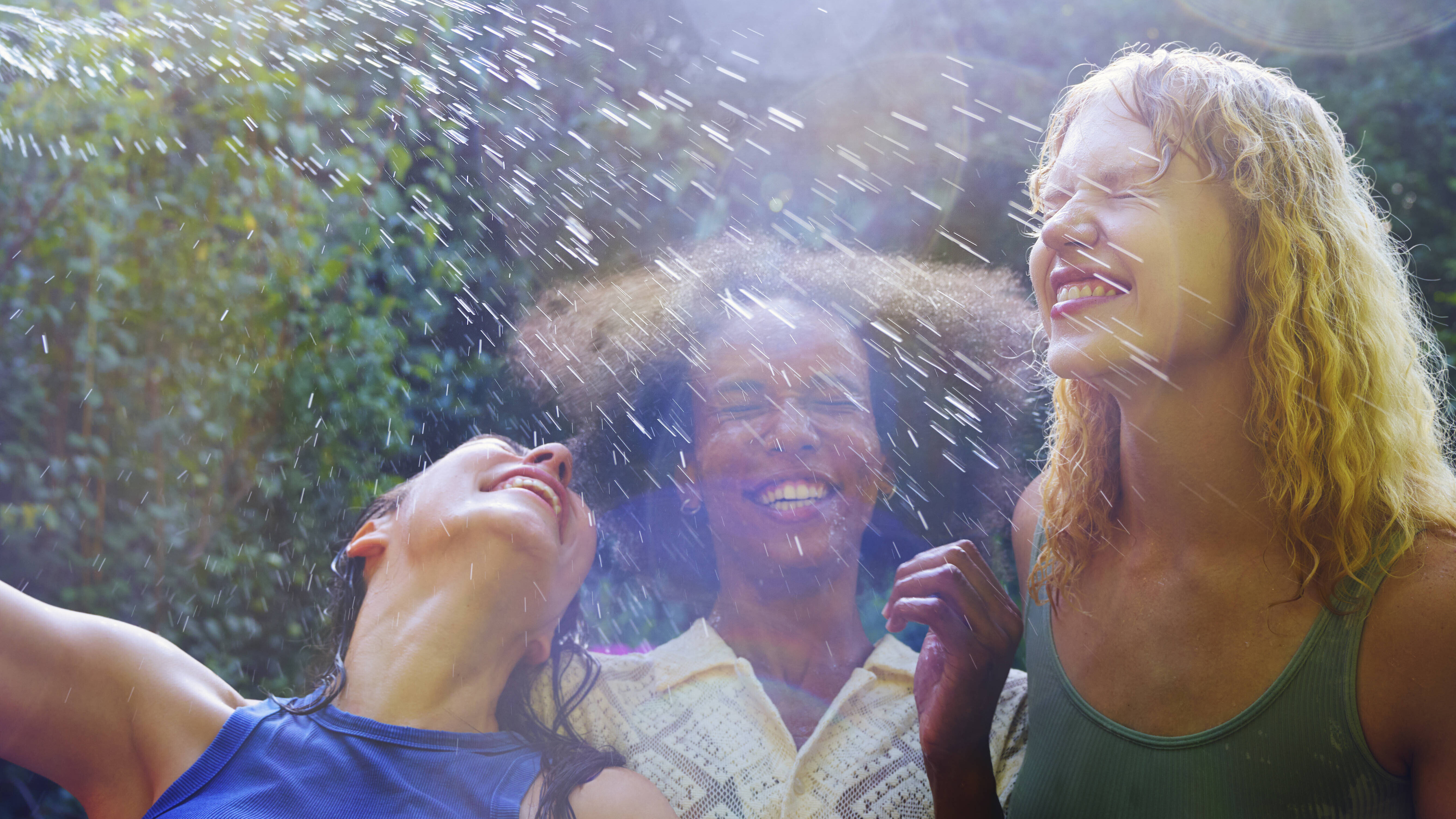 Frauen bespritzen sich mit Wasser und lachen.