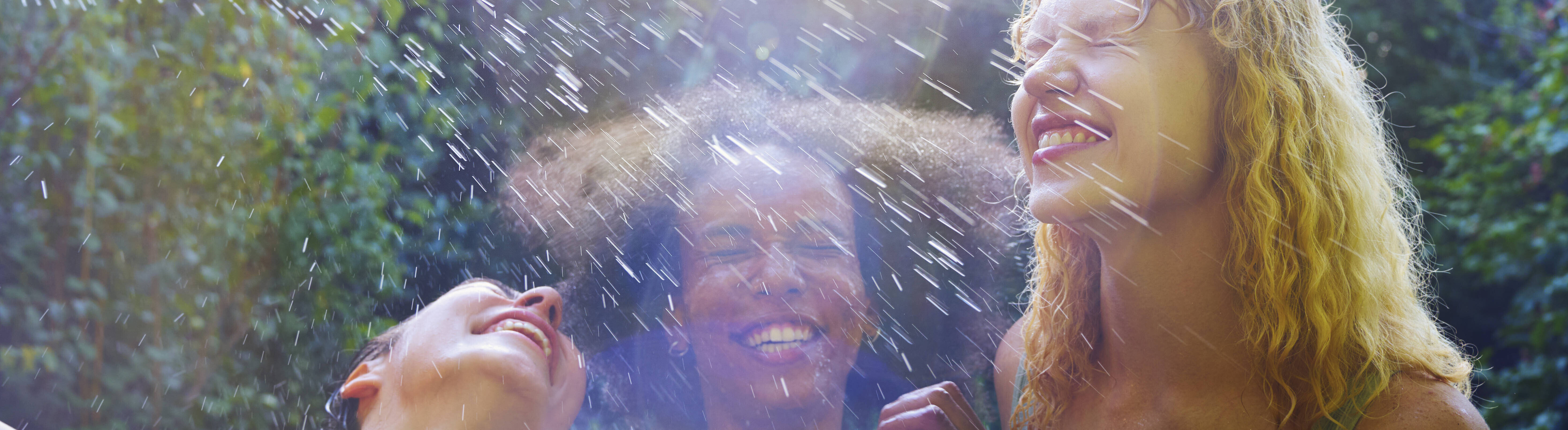Frauen bespritzen sich mit Wasser und lachen.