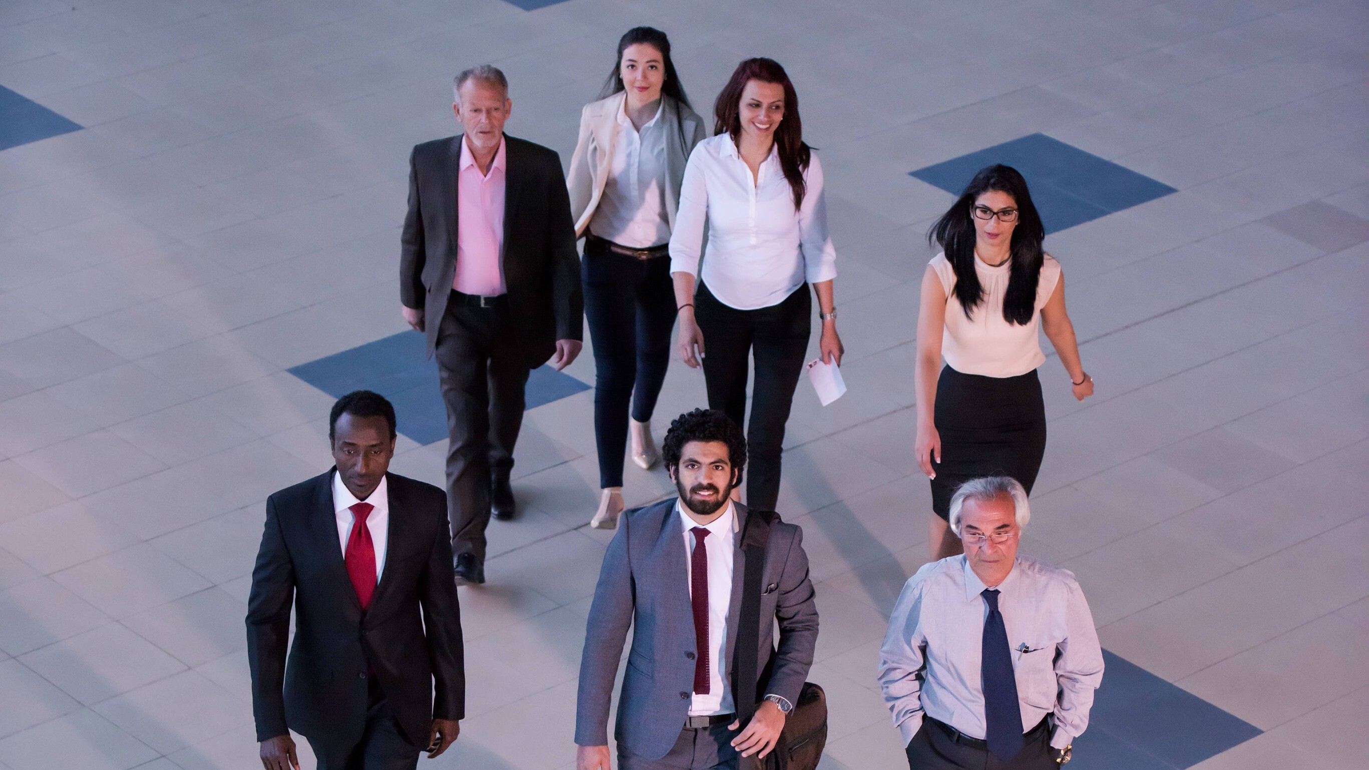 Ein Team aus Fachleuten unterschiedlicher Disziplinen, das selbstbewusst durch eine moderne Firmenlobby schreitet