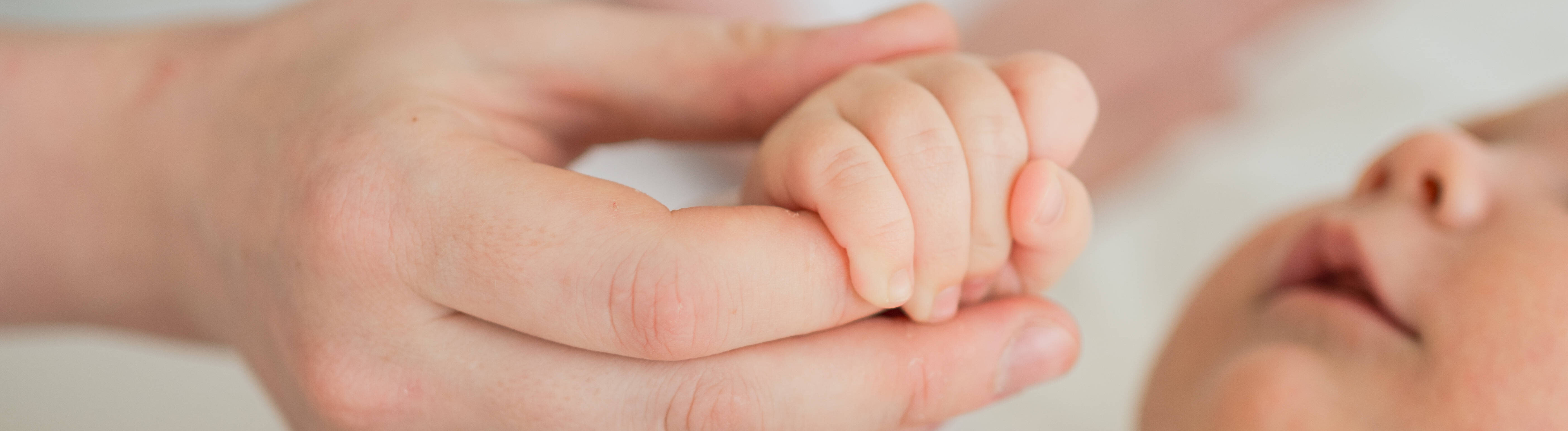 Eine Mutter hält die Hand ihres Babys