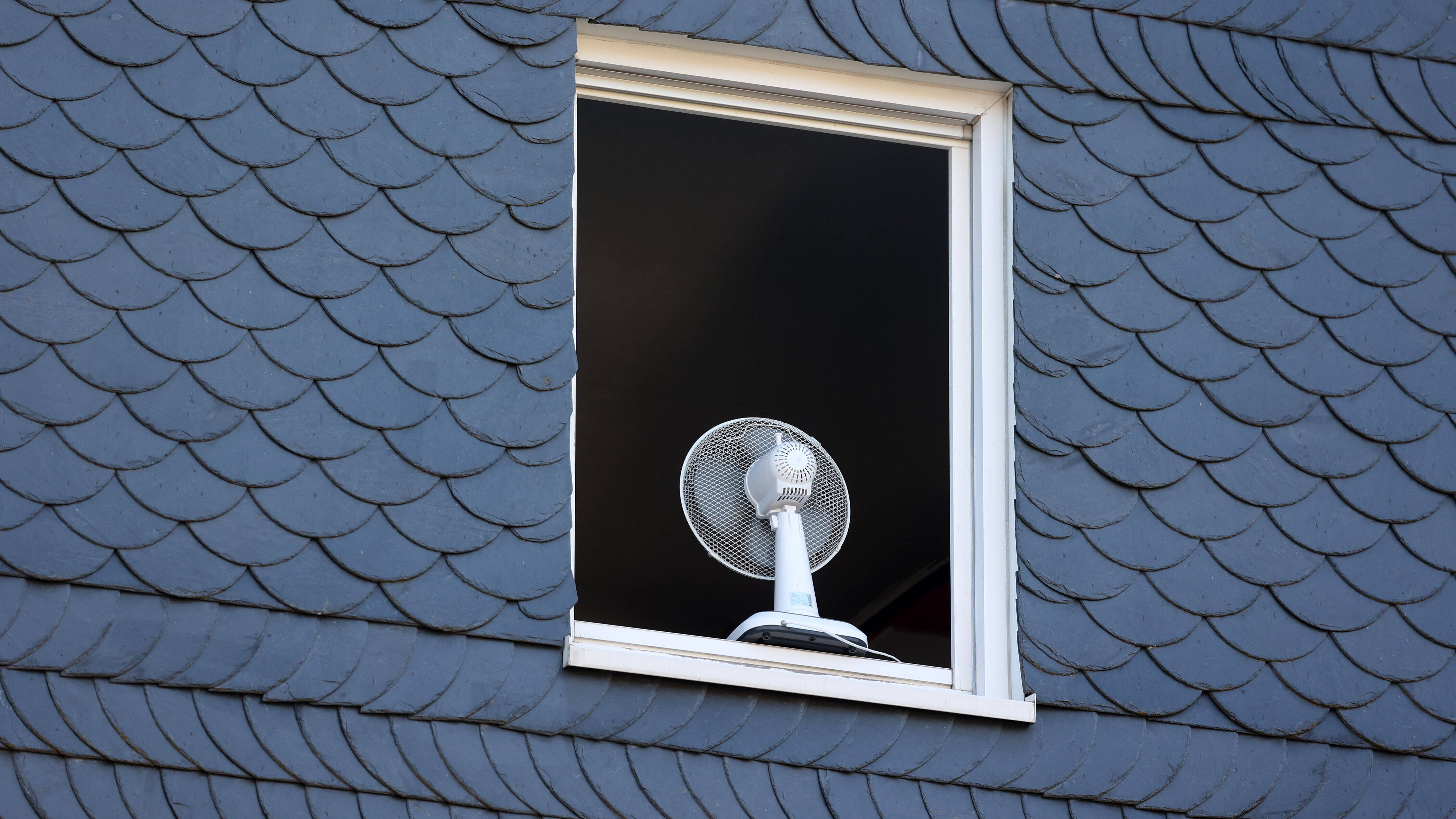 Nach einer sehr warmen Nacht ist ein Fenster in einem Haus am Morgen komplett geöffnet um die Wohnung zu lüften.